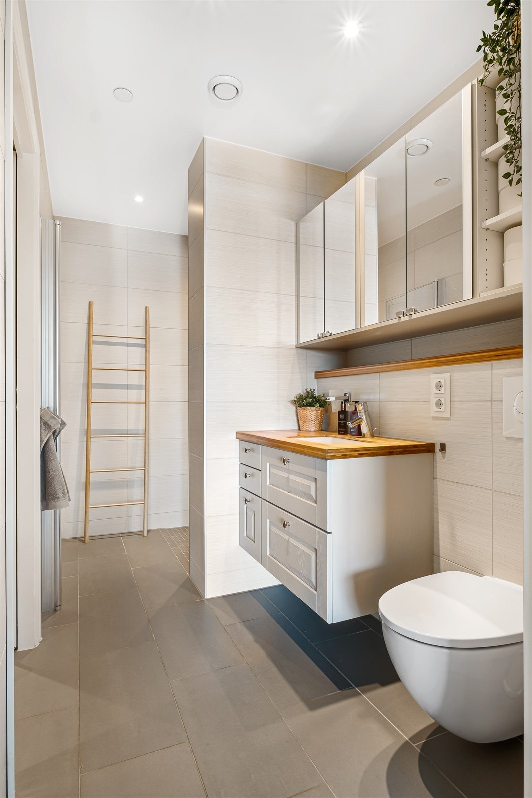 Badet ved entréen er et lyst og stilrent bad med dimmerstyrte downlights i himling, fliselagte overflater og varmekabler i gulv. Galleribilde