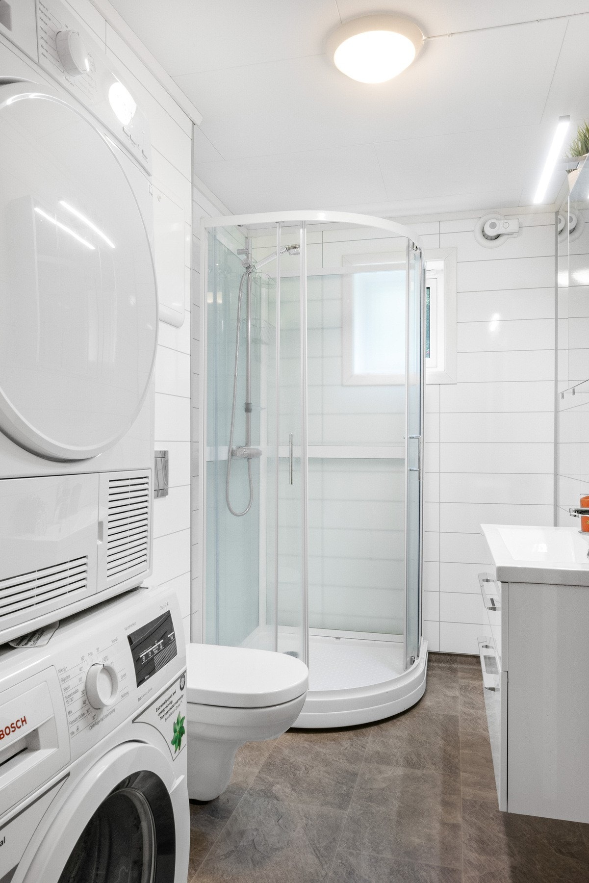 Badet er innredet med baderomsinnredning, speilskap med lys, veggmontert toalett, dusjkabinett og opplegg for vaskemaskin. Galleribilde