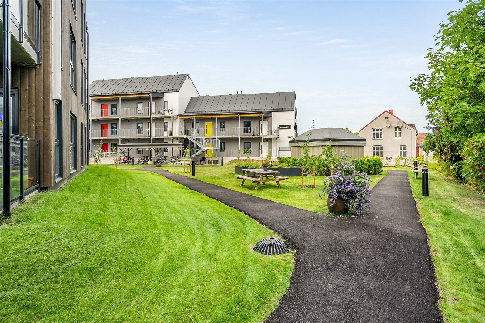 Nydelig felles hage med asfalterte gangstier. Det er sykkelparkering rett ved utgangen til hagen for hvert bygg. Galleribilde