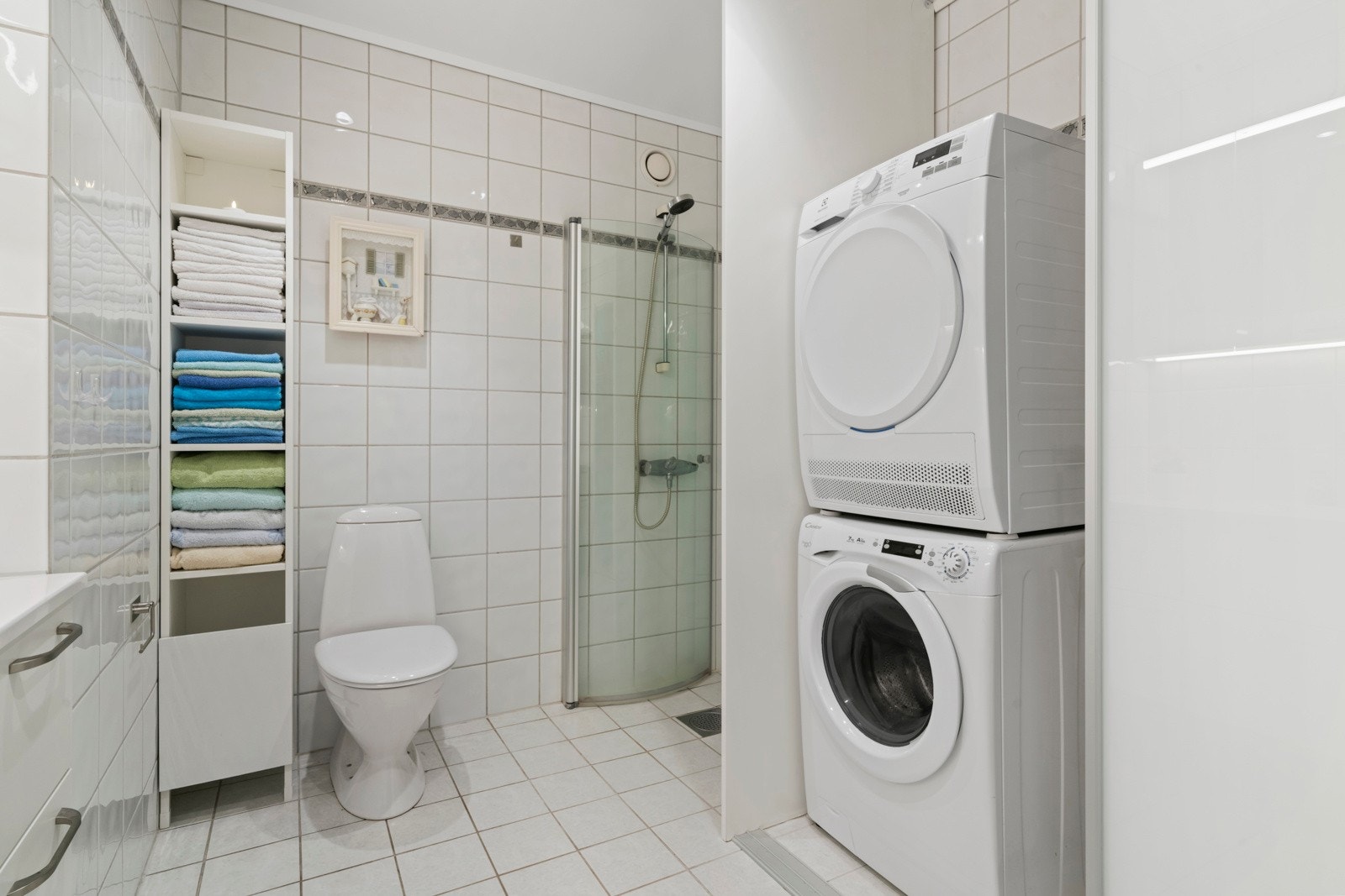 Badet inneholder foldedører i dusj, toalett og baderomsinnredning med heldekkende servant samt belyst speil. Opplegg for vaskemaskin og tørketrommel Galleribilde