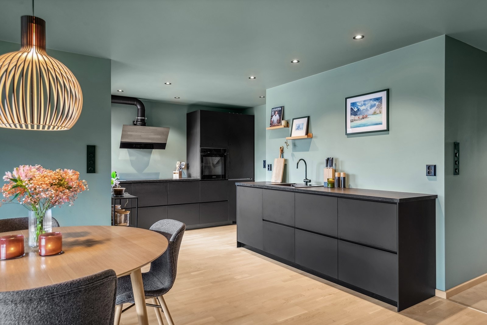 Lekkert kjøkken med sorte slette fronter og benkeplate i stein med oppvaskkum. Galleribilde