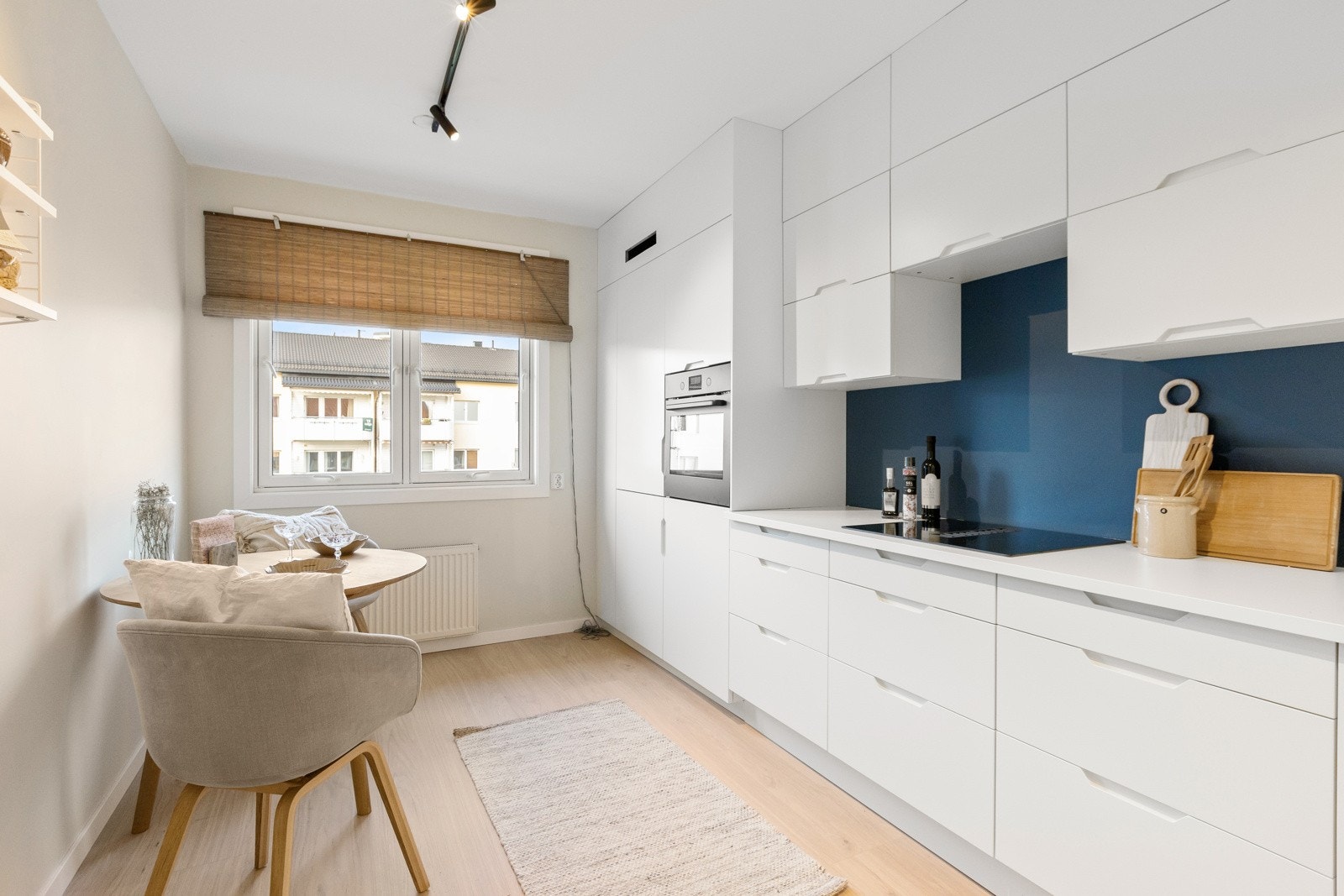 Kjøkkenet er moderne og stilrent med hvite, slette fronter, laminert benkeplate, enkel oppvaskkum og ventilator med kullfilter integrert i steketoppen. Galleribilde