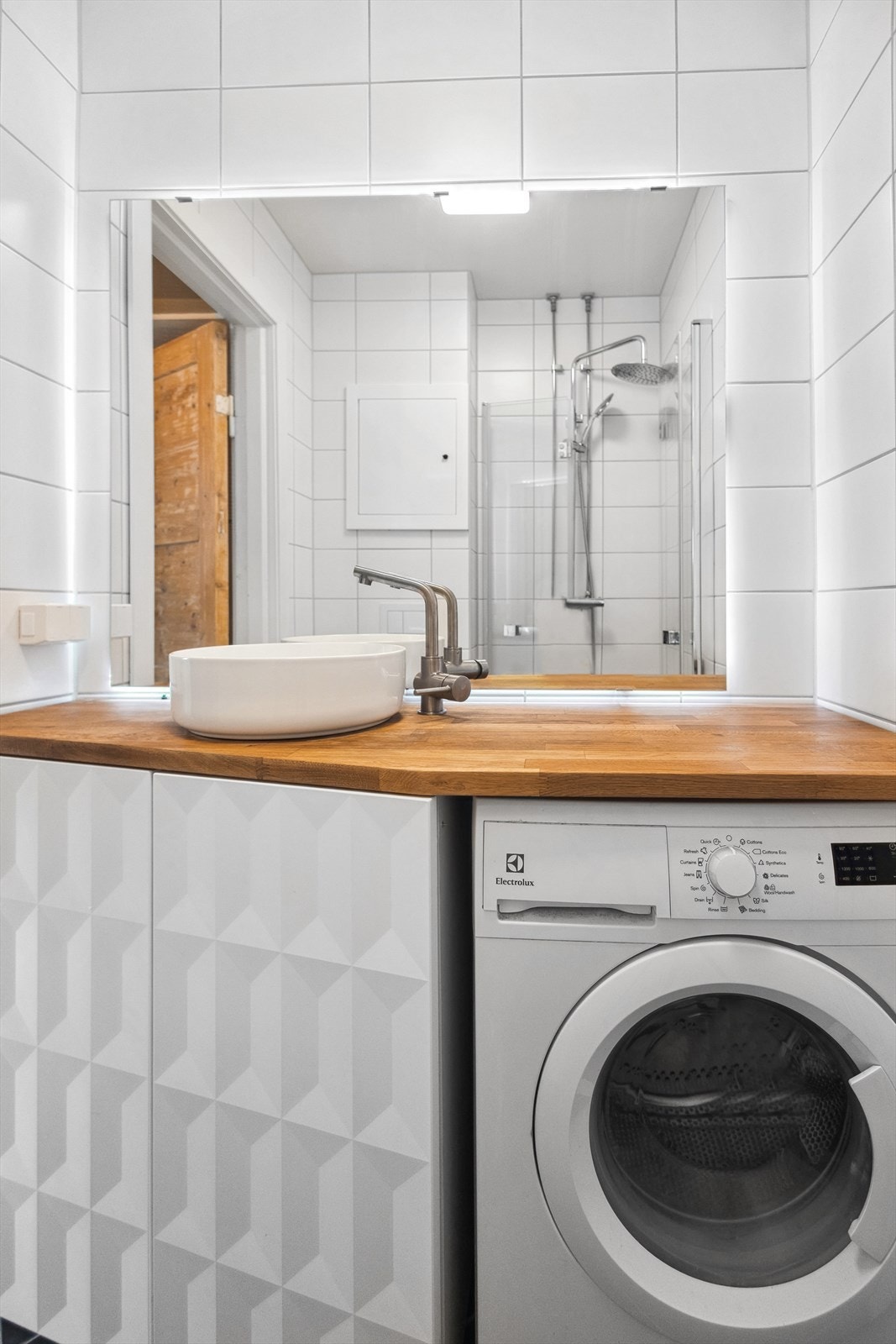 Badet har stort servantskap med vask oppå og vaskemaskin Galleribilde