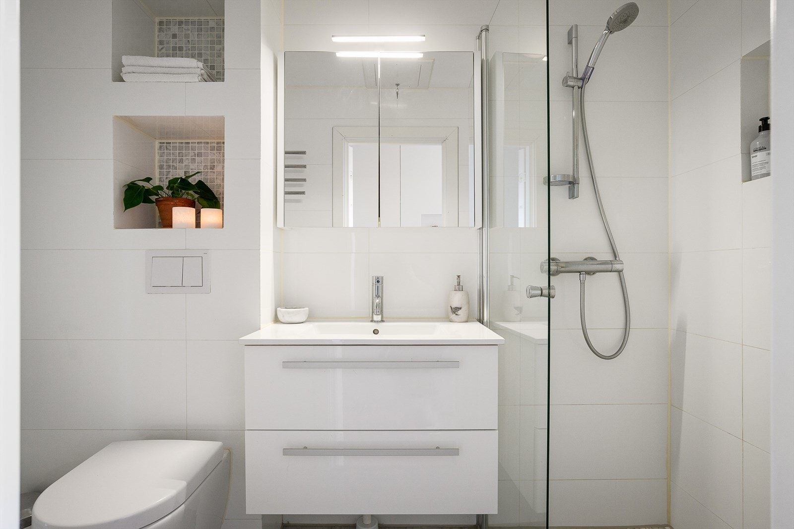 Stilrent bad, rehabilitert i 2018, med flislagte hyller, innebygd sisterne, overskap med speilfronter og benkeskap med glatte fronter. Galleribilde