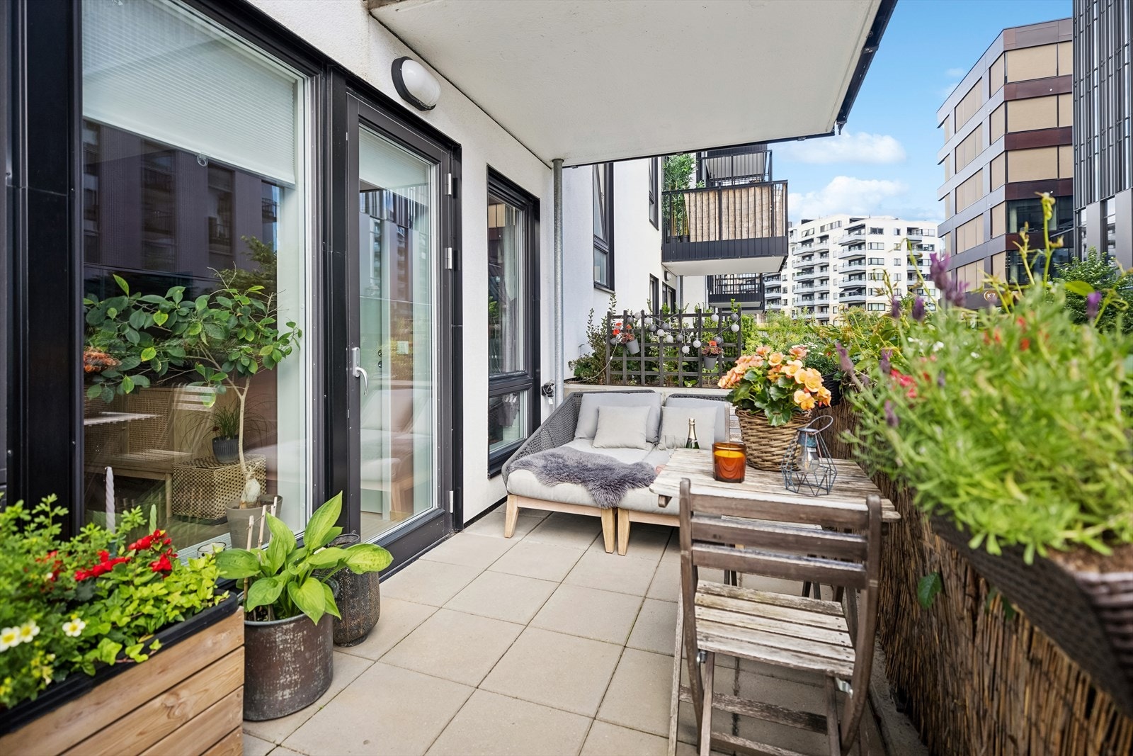 Sydøstvendt balkong med betongheller på gulv med lys på veggen. Denne terrassen ligger høyt til og kan oppleves som en 2.etasje på denne siden av bygget. Galleribilde