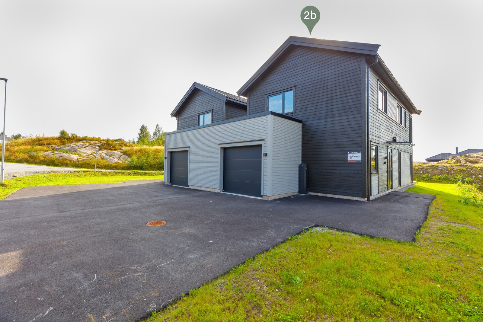 Stor asfaltert gårdsplass og garasje med bod for ekstra lagring. Galleribilde