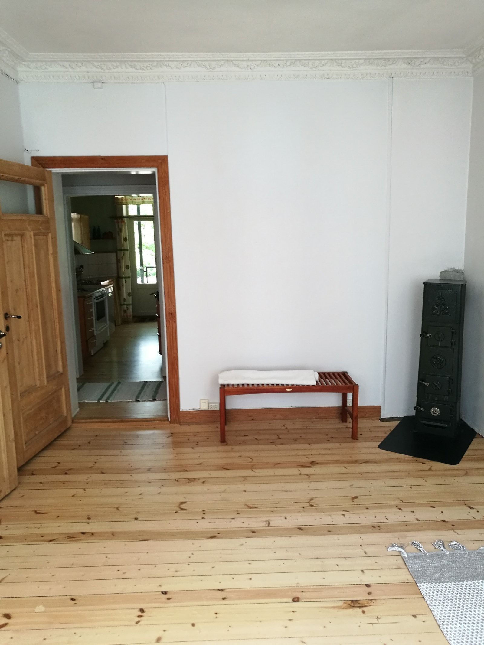 Stue med vedovn og gjennomlys til gang og kjøkken. Sone for spisebord ved vedovnen Galleribilde