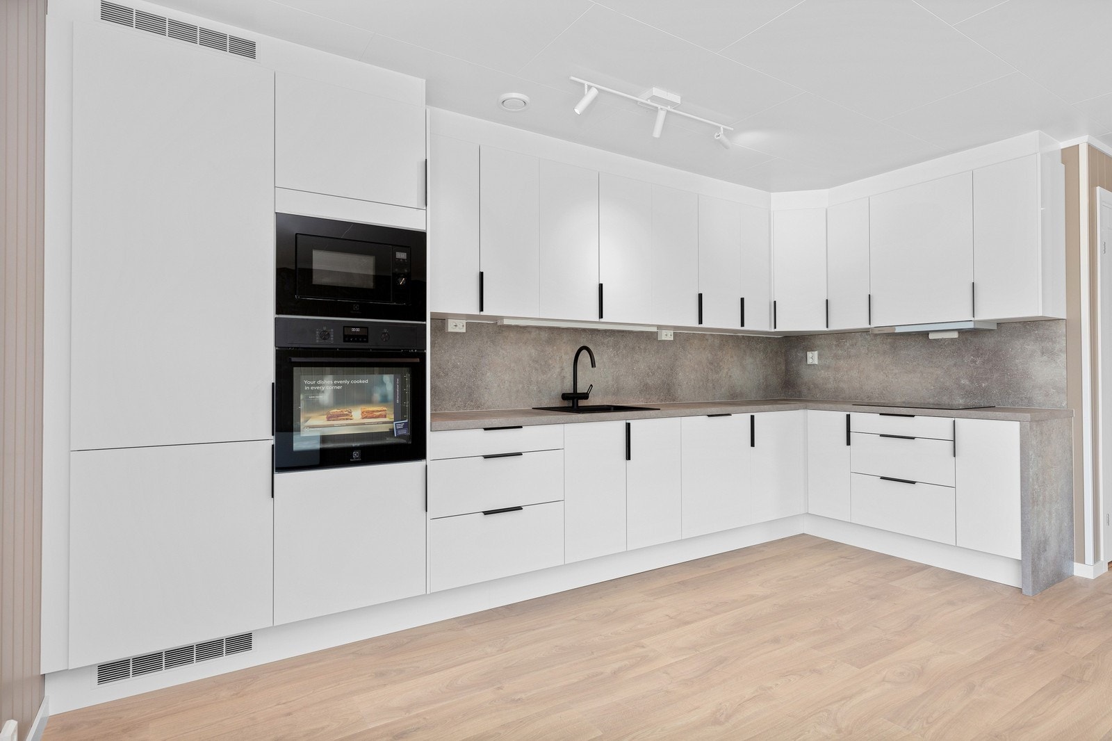 Lyst kjøkken fra Aubo med sorte detaljer, hvitevarer inkludert. Bildene viser en oppgradert leveranse. Foto fra samme type bolig. Avvik kan forekomme. Galleribilde