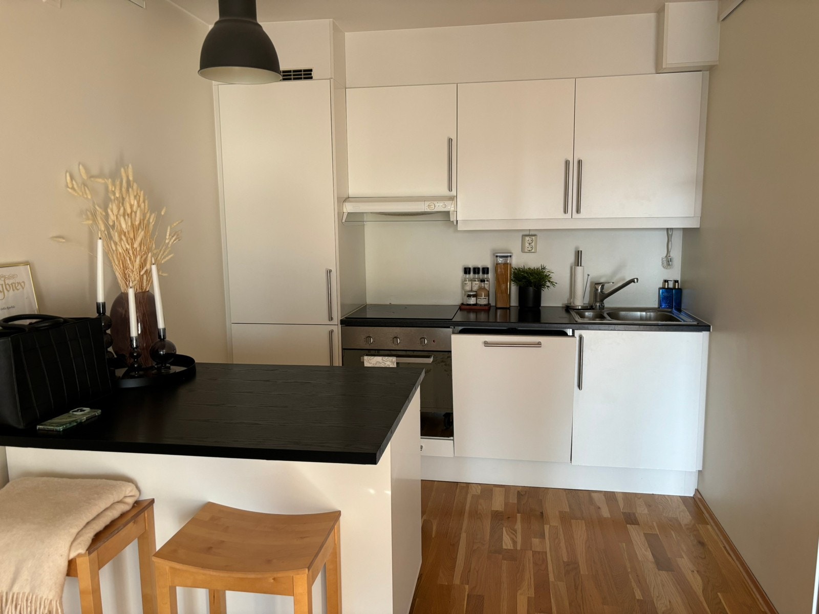 Kjøkken med hvitevarer og øy med spiseplass og to barkrakker. det er plass til et spisebord om ønskelig Galleribilde