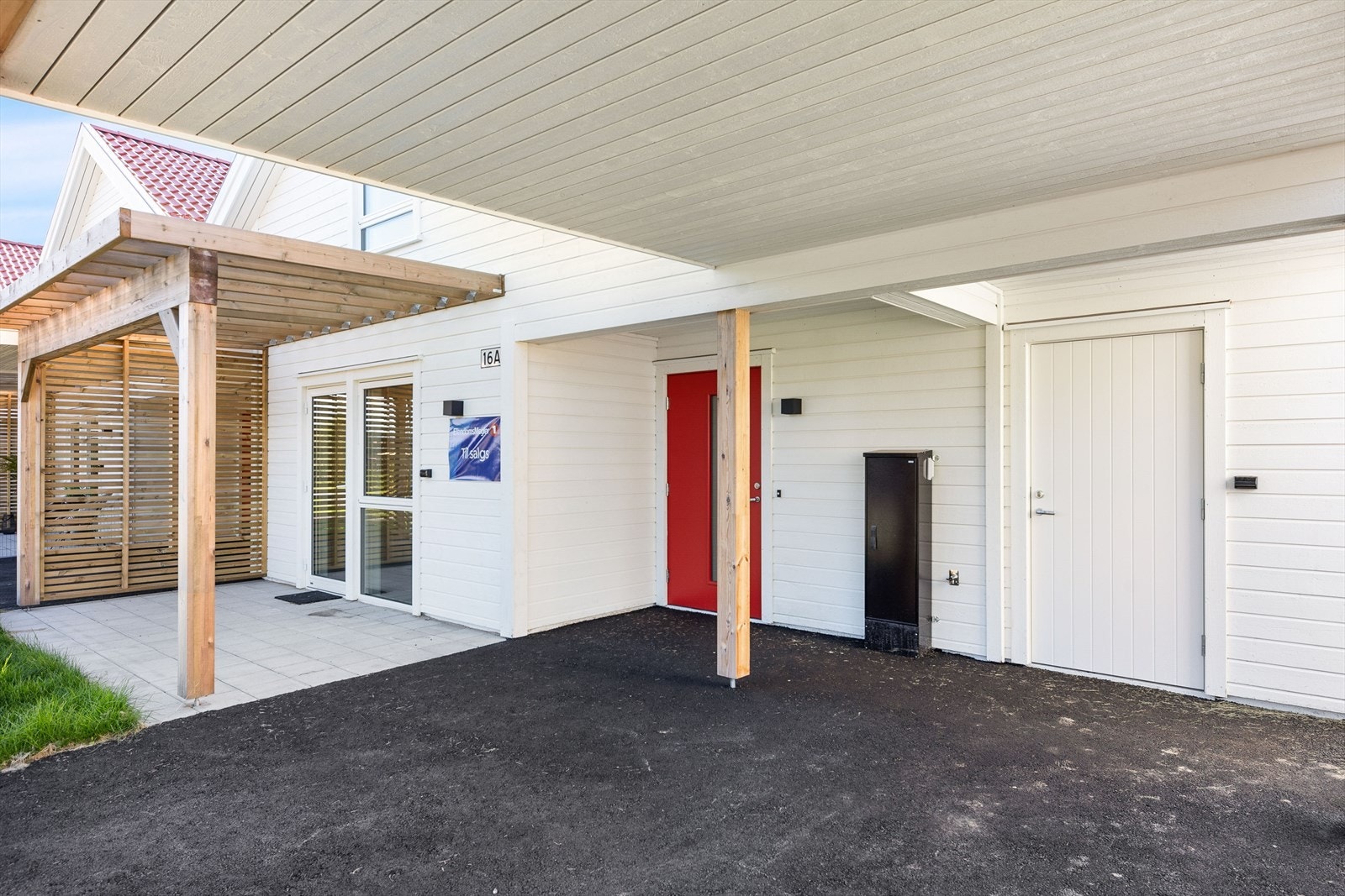 Inngangsparti med carport, bod og en biloppstillingsplass i innkjørselen. Galleribilde