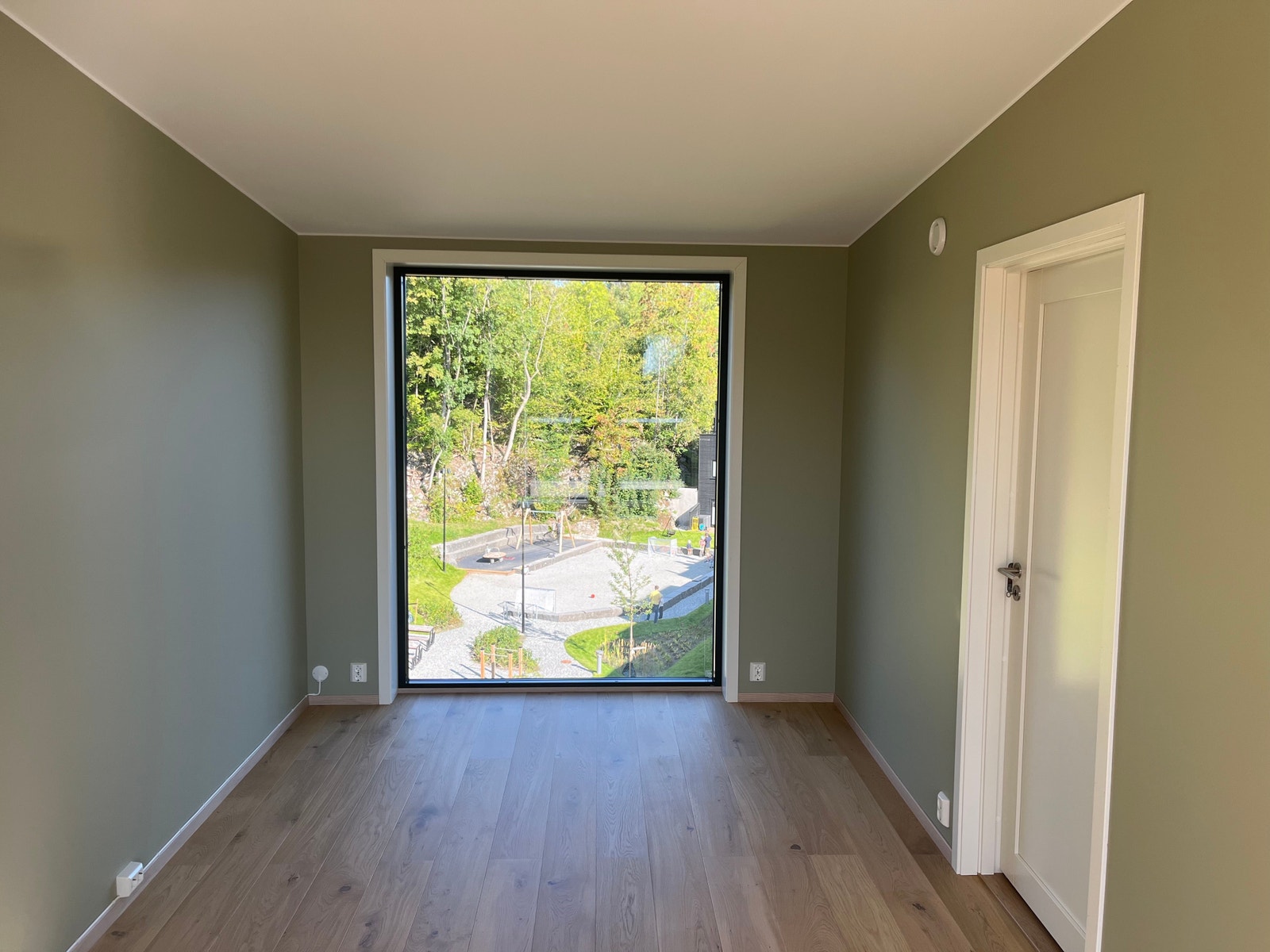 Stue i tredje etasje med utsikt over felles hage og lekeplass Galleribilde