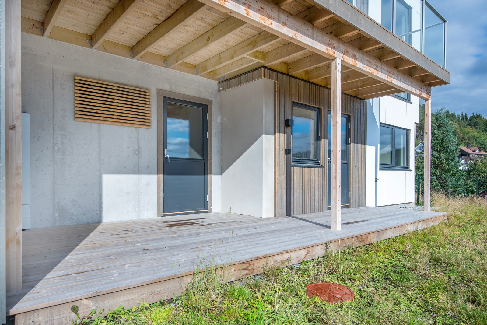 Frå sørsida er det inngang til den store boda under carport. Galleribilde