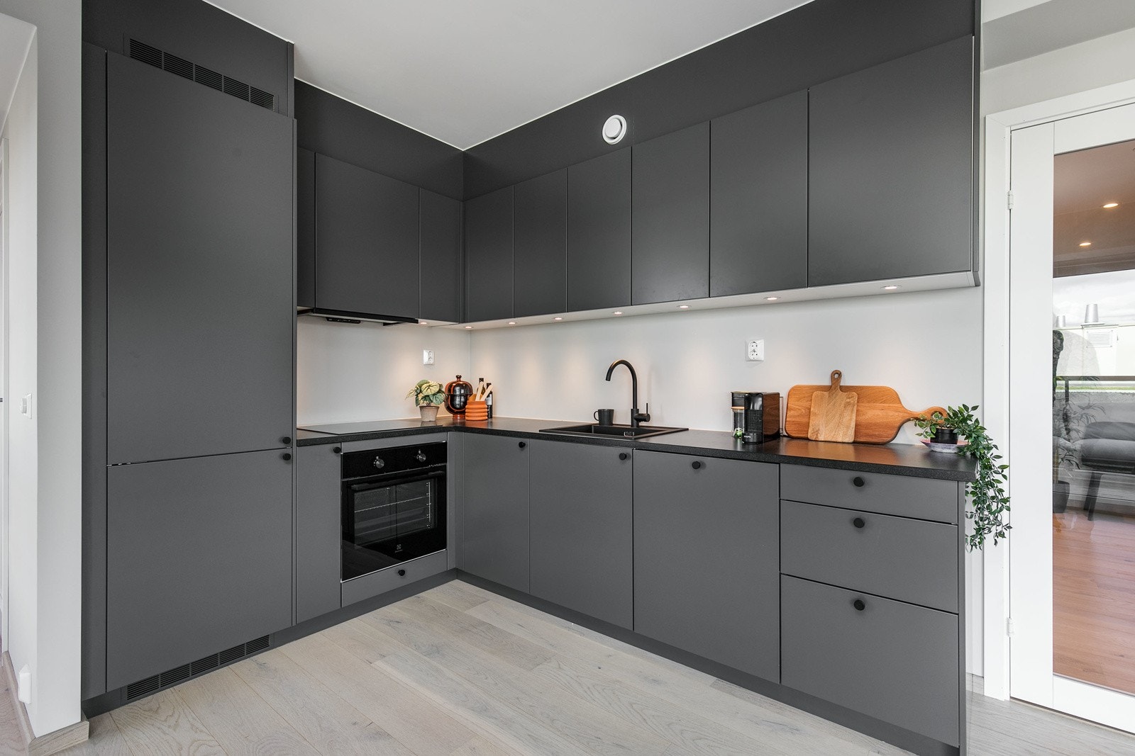 Kjøkken med sorte detaljer og alle integrerte hvitevarer Galleribilde