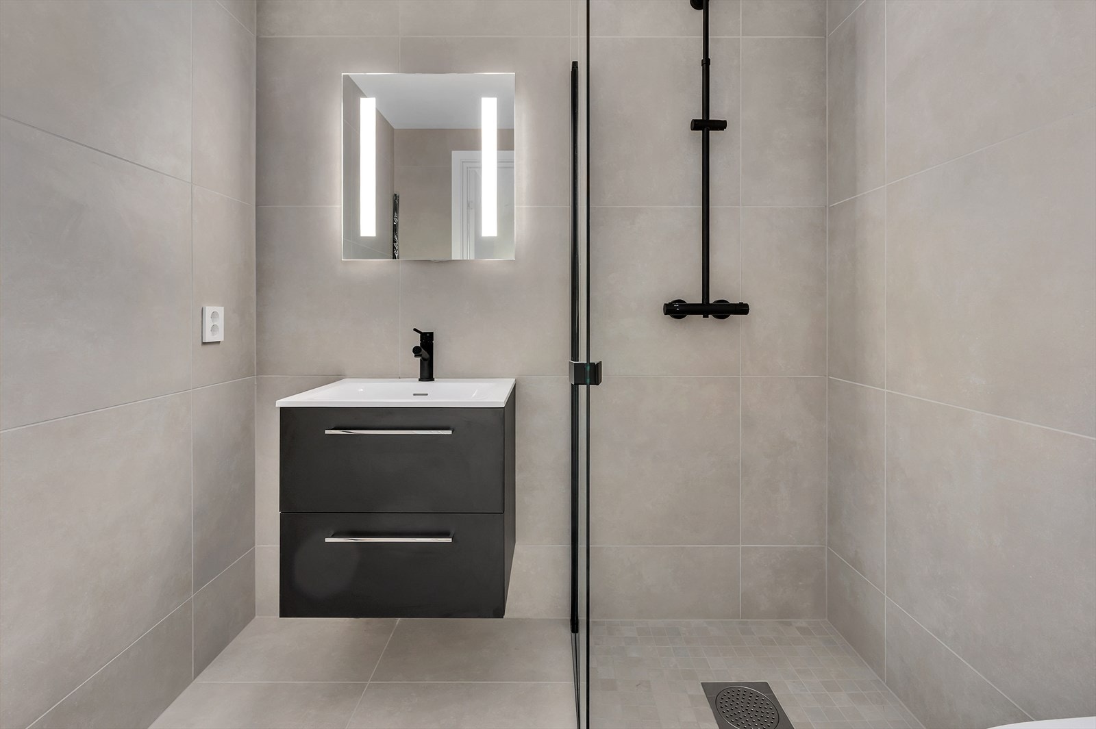 Moderne bad med dusjhjørne, stilren innredning og rene linjer. Lyse fliser skaper en romslig og innbydende atmosfære. Foto fra bolig nr 5. Galleribilde