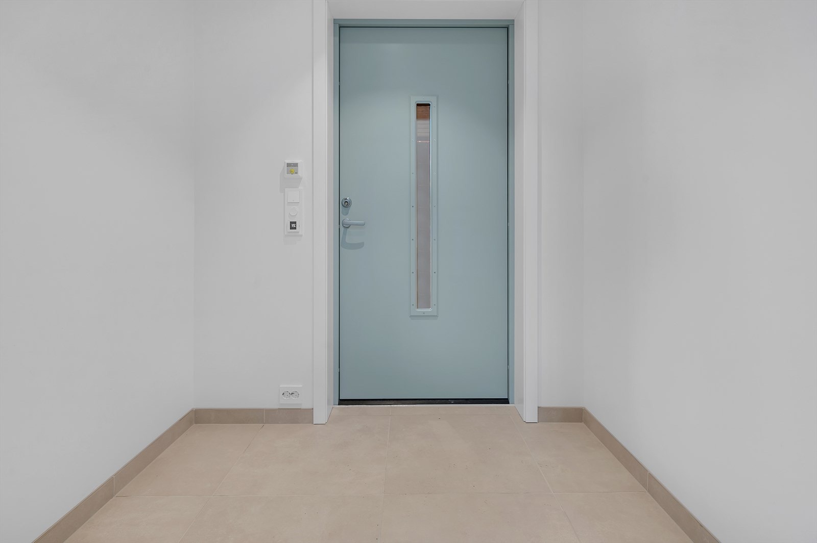 Moderne inngangsparti med lys, stilren dør og praktisk flislagt gulv. Perfekt for å ønske gjester velkommen hjem. Det er varmekabler i gulv. Foto fra bolig nr 5. Galleribilde