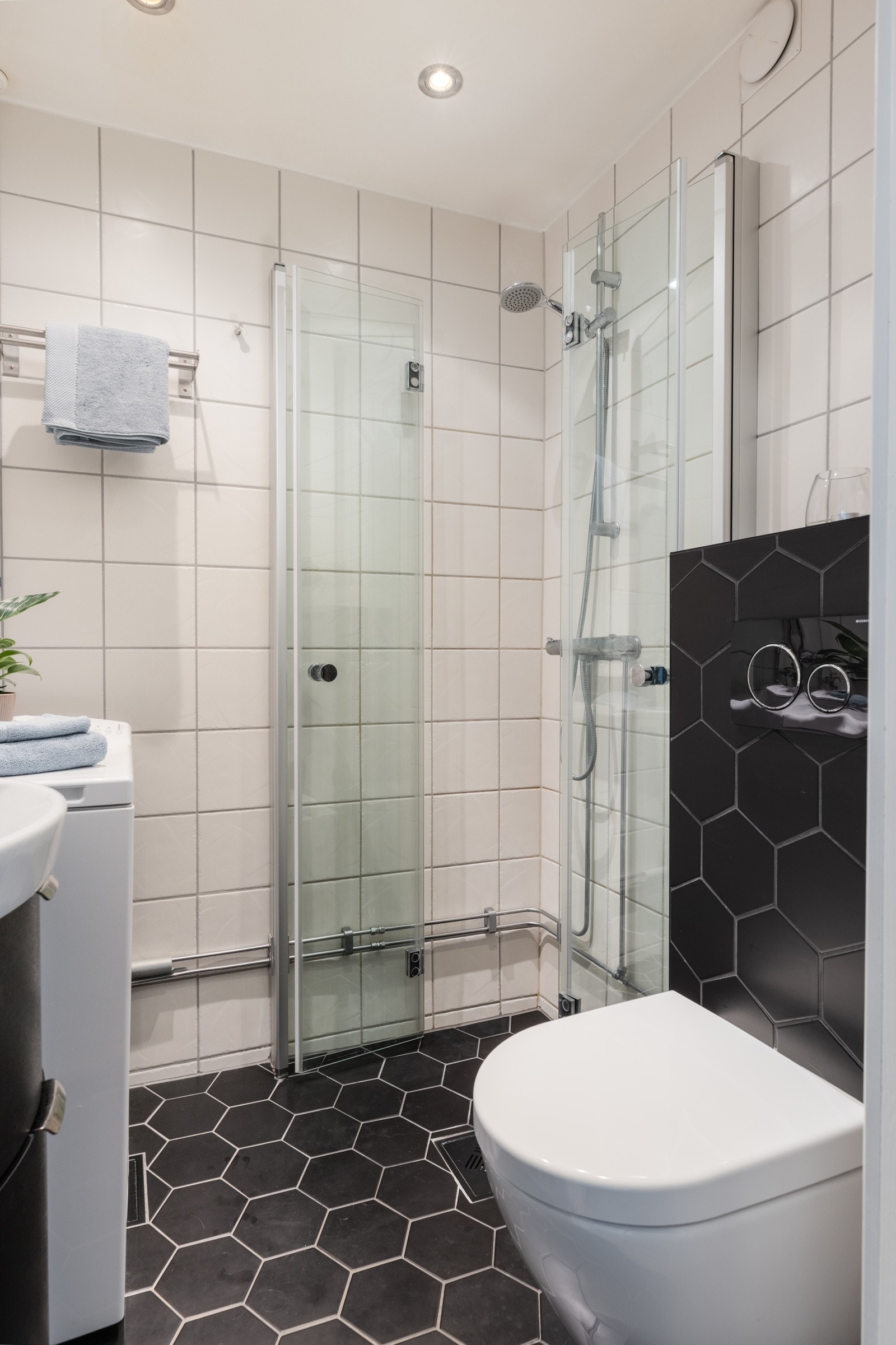 Flislagt bad med opplegg for vaskemaskin, dusjsone, servantskap med oppbevaring og toalett. Galleribilde