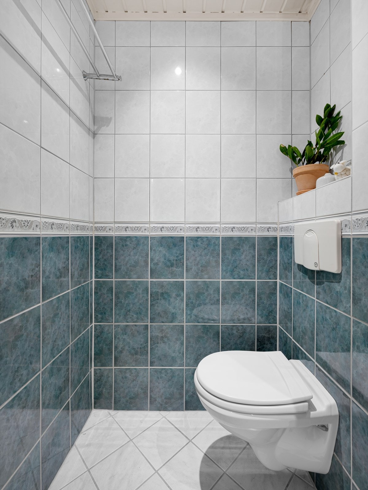 Badet er innredet med veggmontert WC, dusjhjørne med dusjvegger, servant og opplegg for vaskemaskin/tøretrommel. Galleribilde
