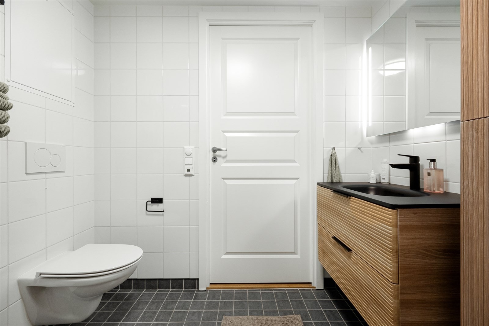 Innredning bestående av servantskap med heldekkende servant, speil med belysning, vegghengt wc, dusjhjørne med svingdører og opplegg for vaskemaskin. Galleribilde