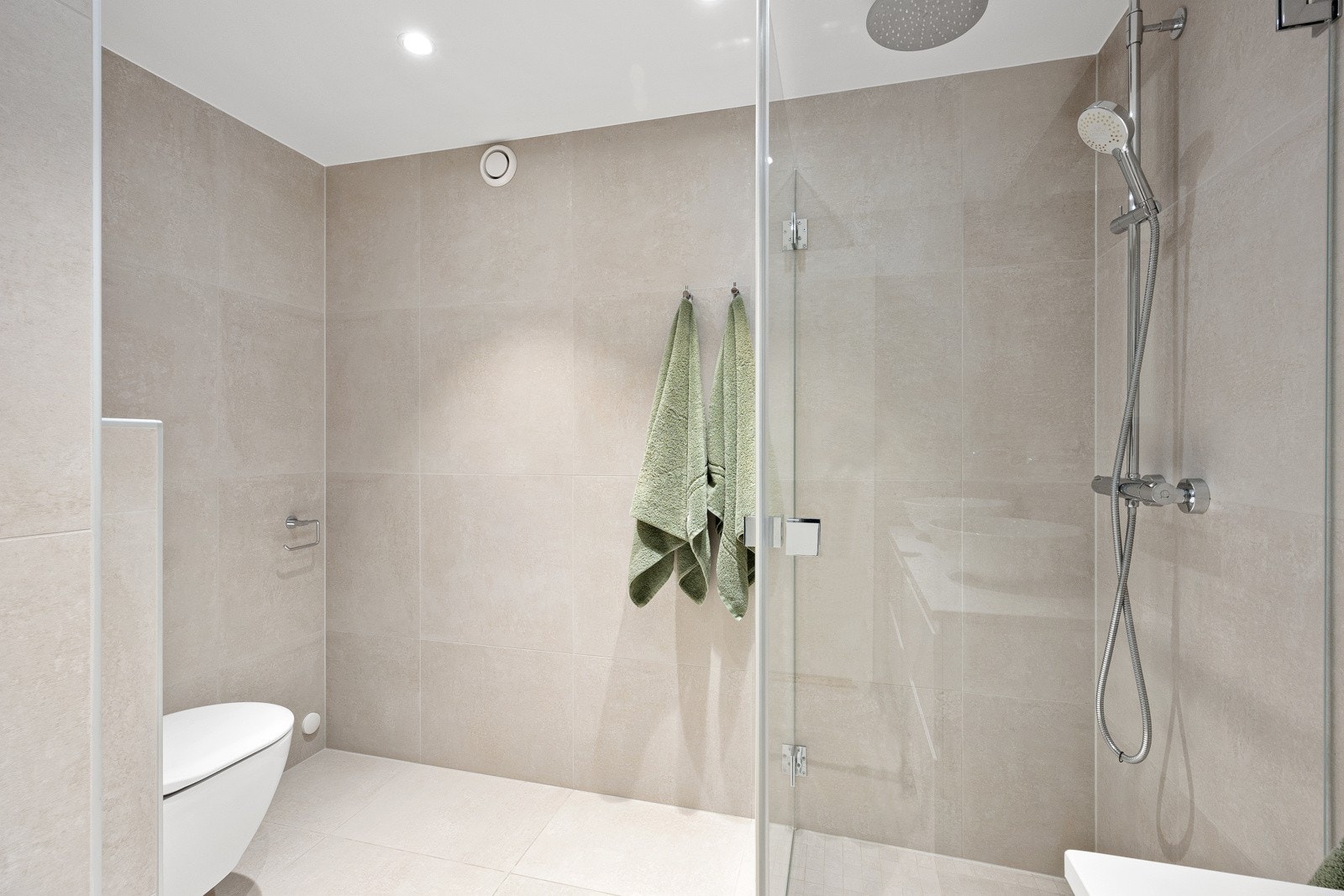 I dusjhjørnet er det både regndusj og hånddusj, skjermet bak rette, innfellbare glassdører. Galleribilde