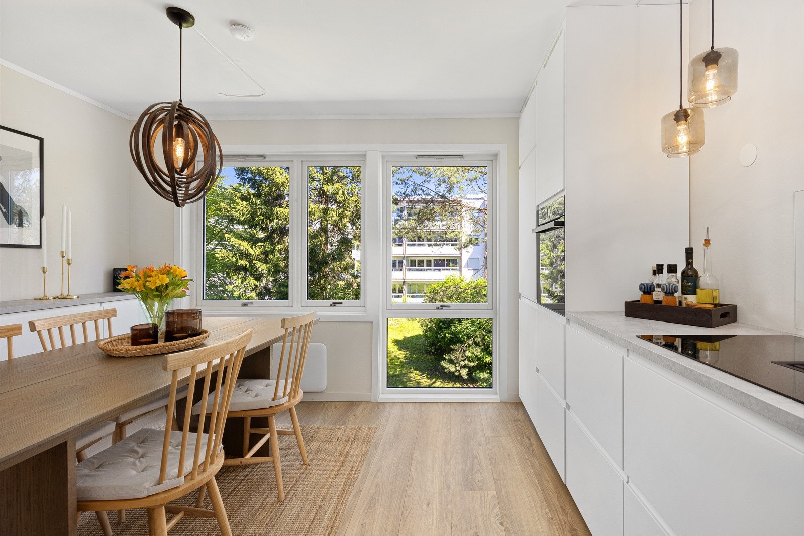 Et trefags vindu, hvor ett går helt ned til gulvet trekker de grønne, frodige fellesarealene inn i rommet. Galleribilde