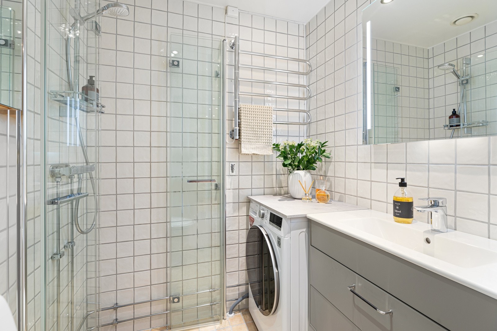 Flislagt baderom i lys utførelse. Dusjnisje med innfellbare dører for plassbesparing Galleribilde