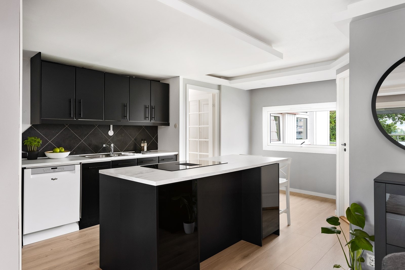 Veggen mellom stuen og kjøkkenet ble revet i 2020 til fordel for en mer åpen kjøkkenløsning. Kjøkkenet er fra IKEA og er utstyrt med slette folierte fronter, en laminatbenkeplate, samt fliser på bakveggen. Galleribilde