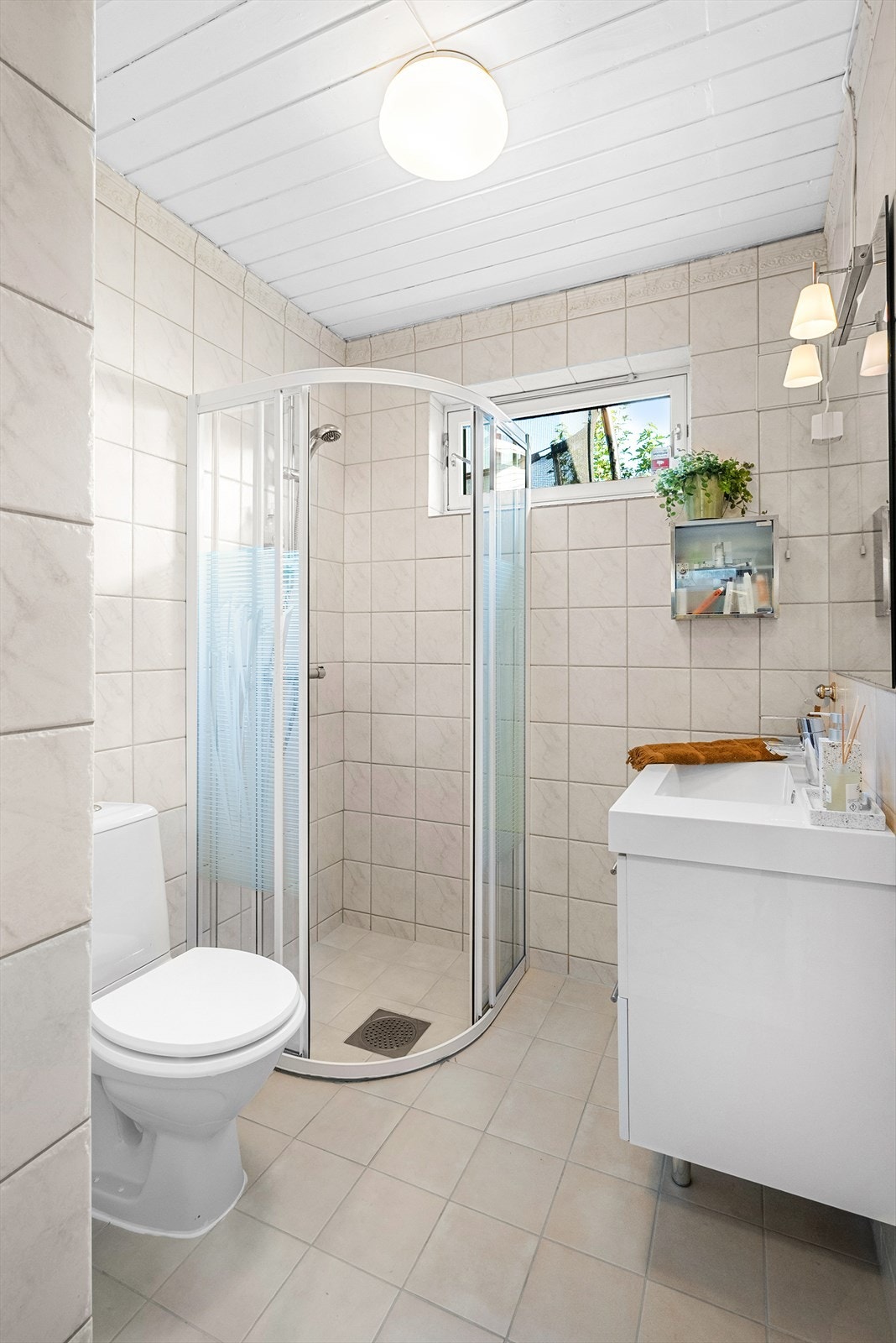 Baderom med elektrisk gulvvarme. Badet er innredet med servant på innredning, klosett og dusjhjørne med faste vegger. Galleribilde