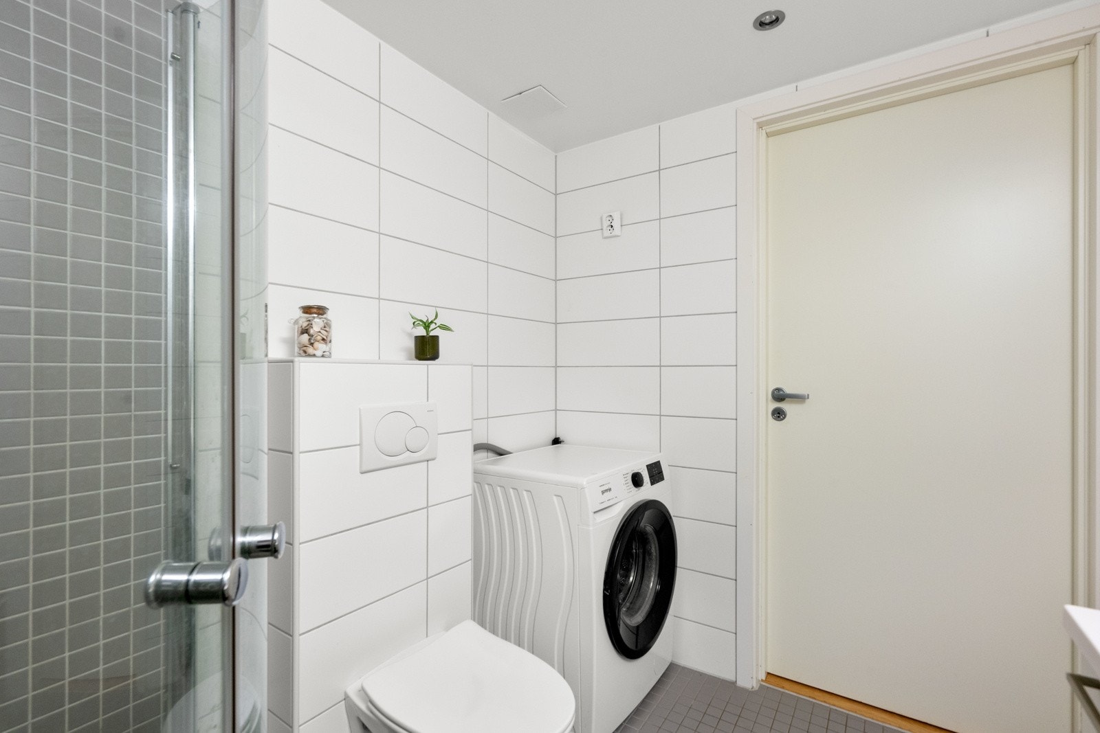 Innredet med veggmonterte dusjdører, servant med underskap, speil med lys over og veggmontert wc. Galleribilde