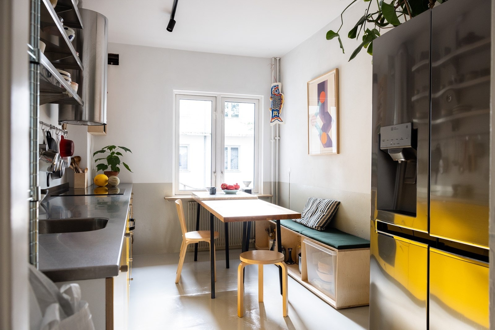 Kjøkkenet i leiligheten har et industrielt preg, med en dyp benkeplate i rustfritt stål og gulv som er flytsparklet med epoxymaling. Her er det også plass til en spisegruppe, perfekt for å nyte morgenkaffen mens morgensolen strømmer inn gjennom vinduene. Galleribilde