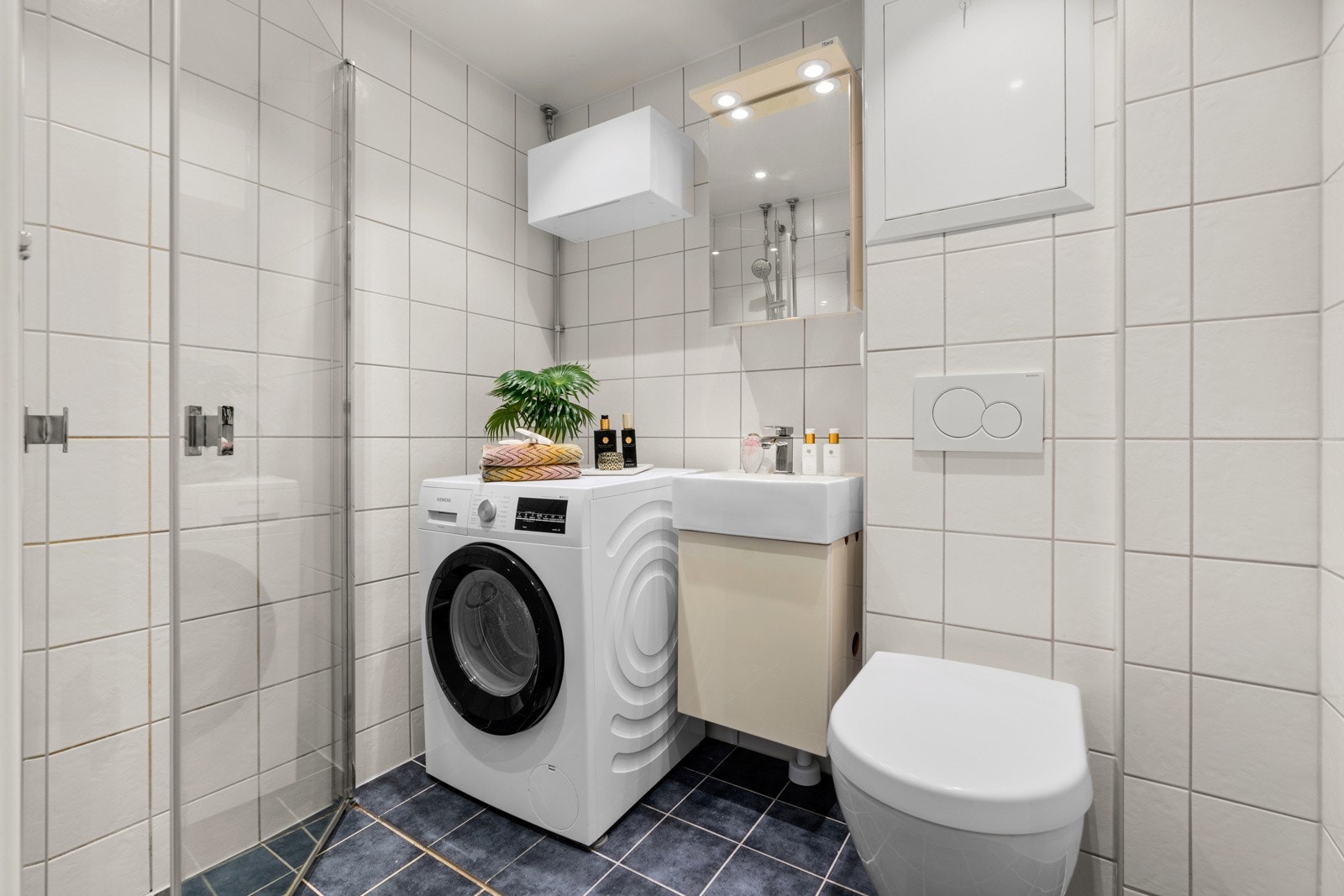 Pent flislagt bad fra 2015/16, modernisert i regi av borettslaget. Badet er utstyrt med servantskap, speilskap med lysarmatur, veggmontert wc, dusjhjørne med svingdører og opplegg for vaskemaskin Galleribilde