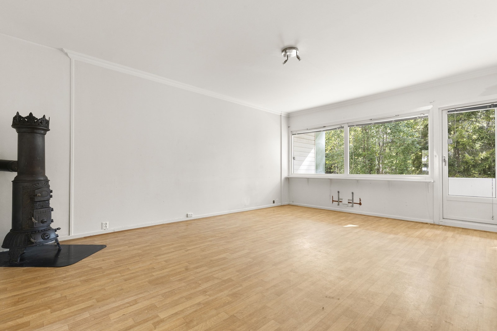 Romslig stue med store vindusflater. Vedovn i hjørnet. Galleribilde