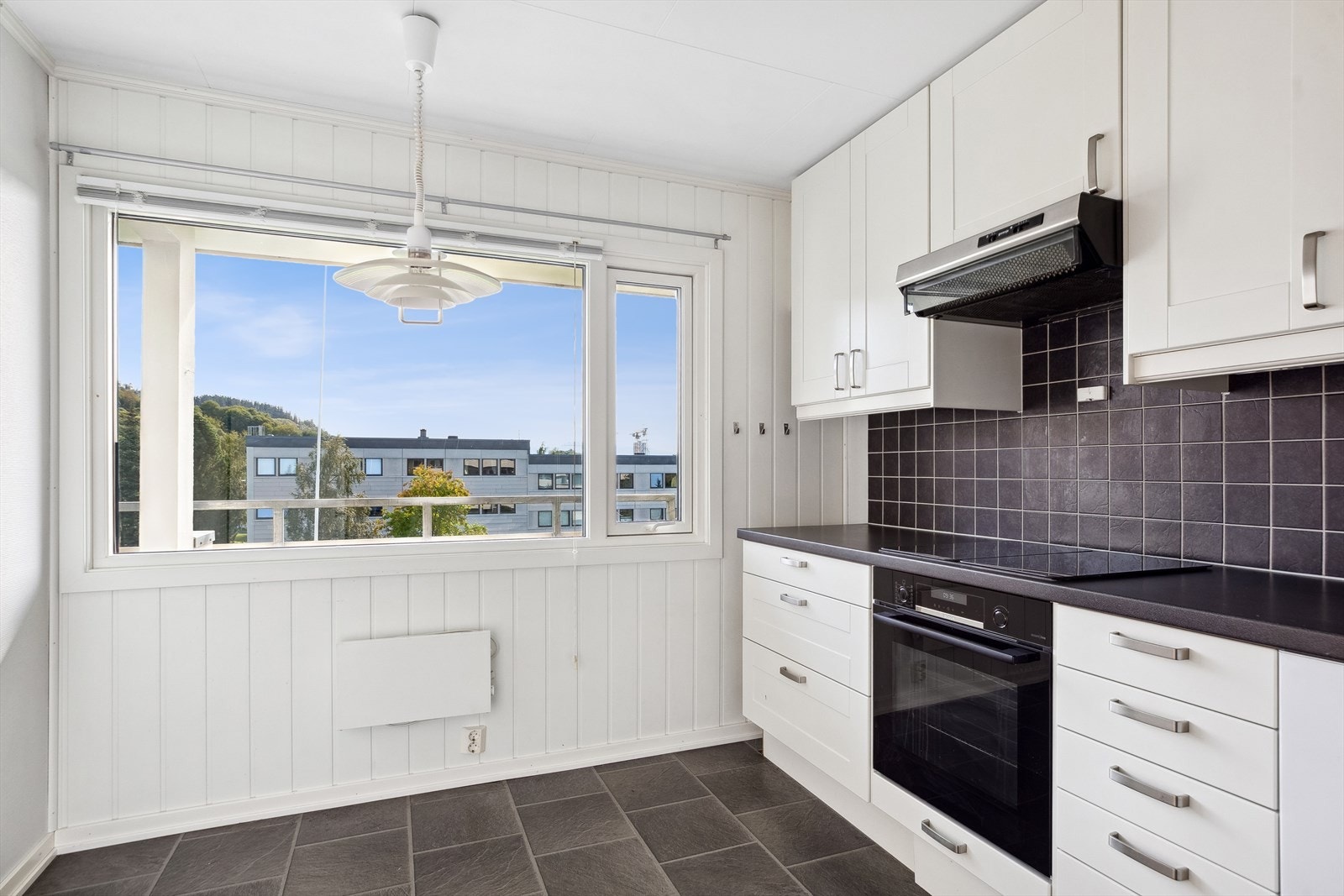 Kjøkkenet ligger i eget rom og har hvit innredning med mørke benkeplater. Galleribilde