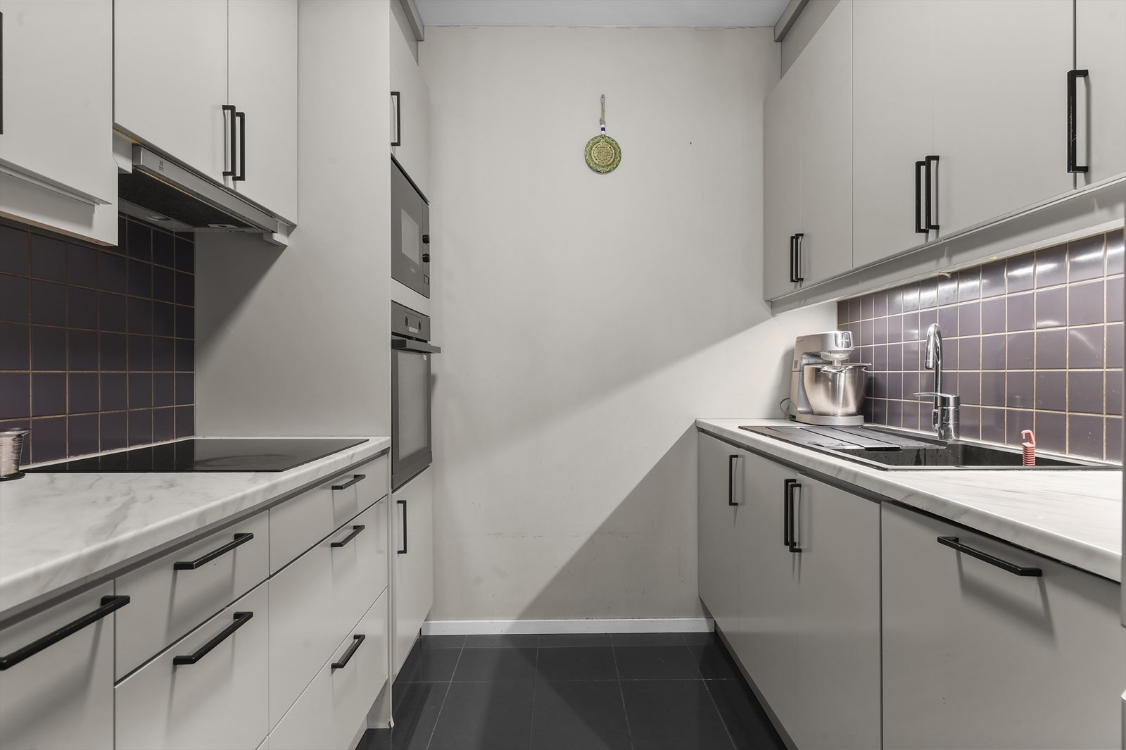 Kjøkkenet er innredet med induksjonstopp, stekeovn, oppvaskmaskin og mikrobølgeovn Galleribilde