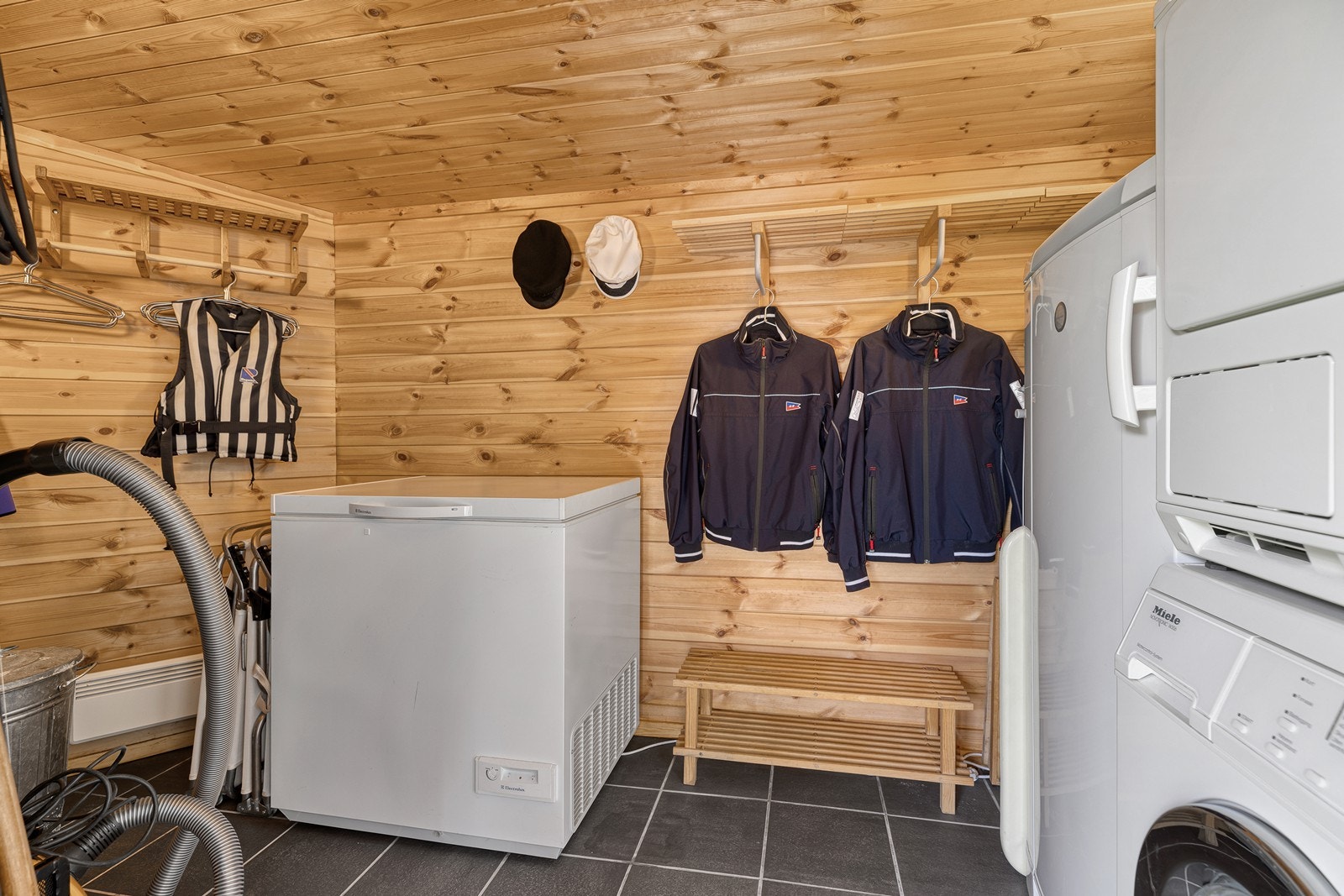 Vaskerom med fliser på gulv og trepanel på vegger Galleribilde