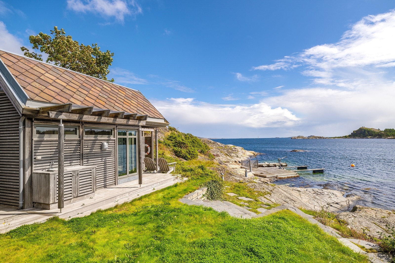 Arkitekttegnet landsted helt i sjøkanten, med en lang strandlinje som inkluderer en brygge og magiske svaberg Galleribilde