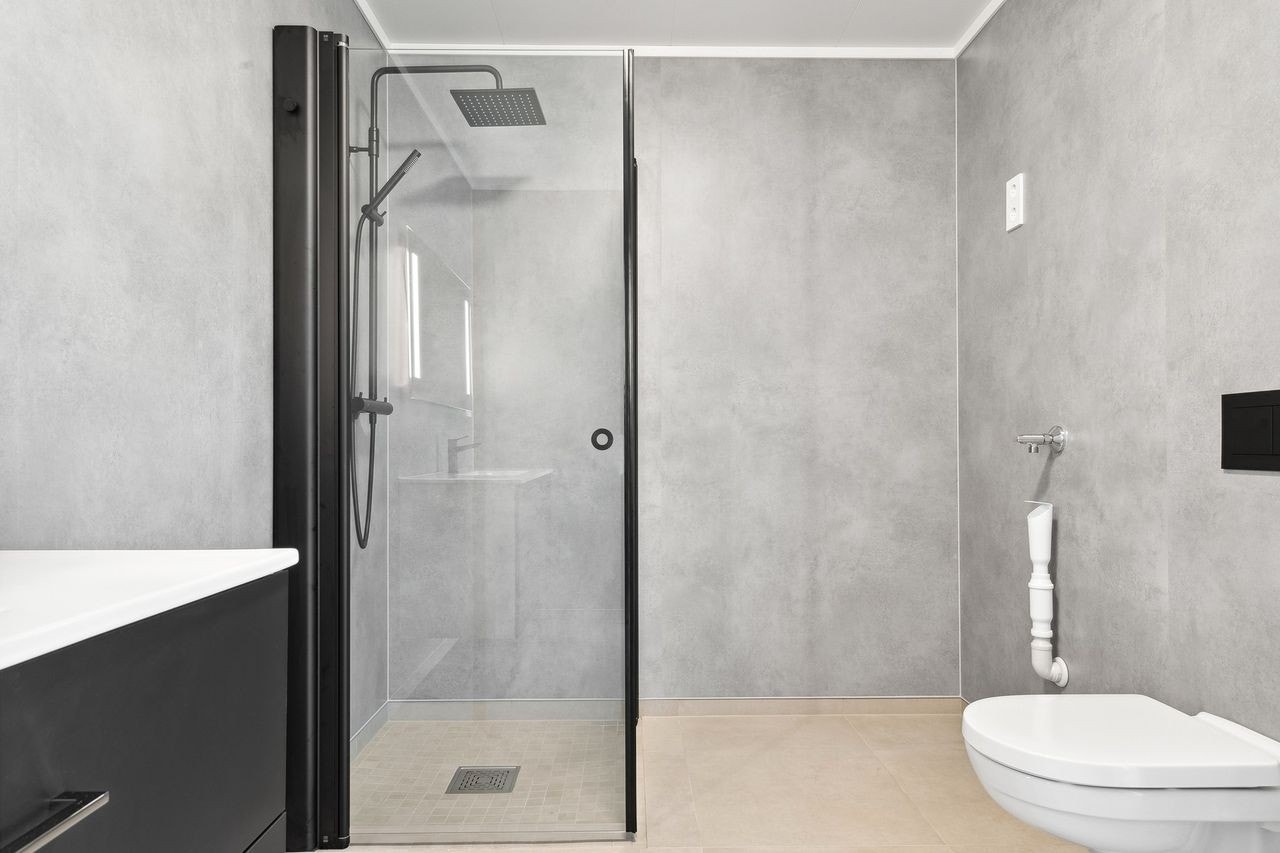 Vegghengt toalett, dusjhjørne, servant og opplegg for vaskemaskin her nede også. Galleribilde