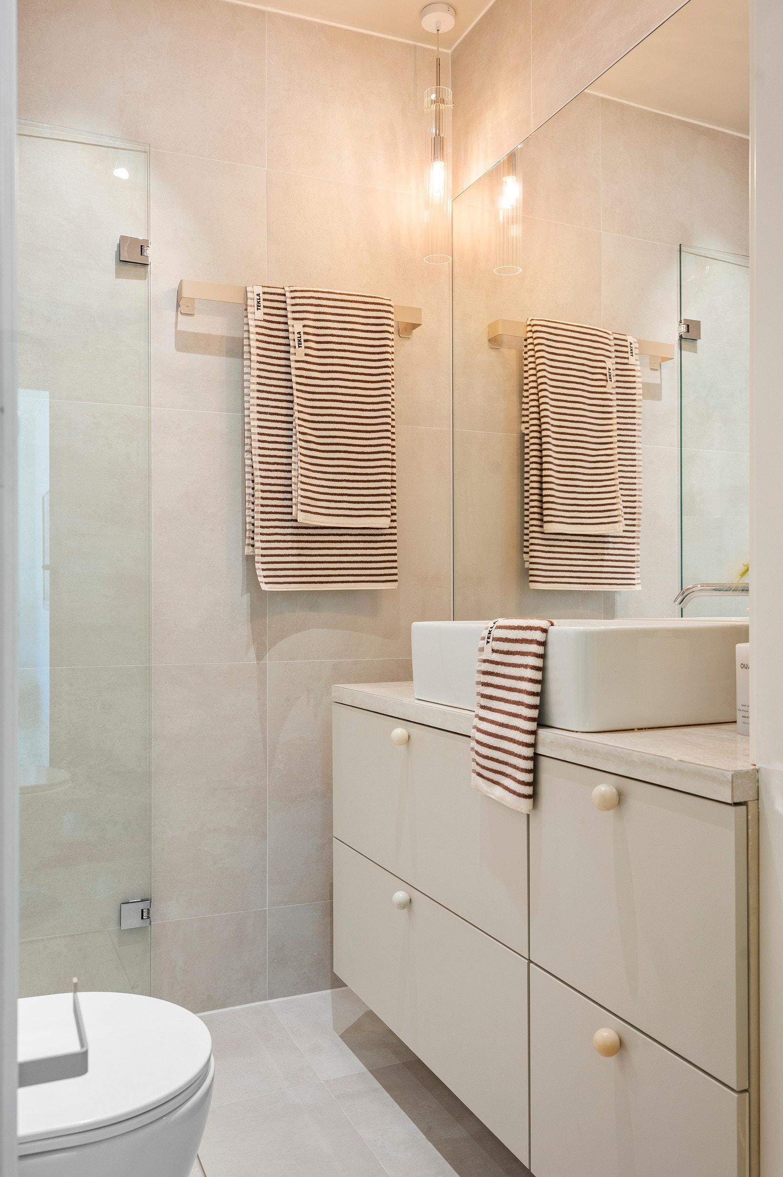 Bred innredning med heldekkende benkeplate, ovenpåliggende servant og stort innmurt speil. Galleribilde