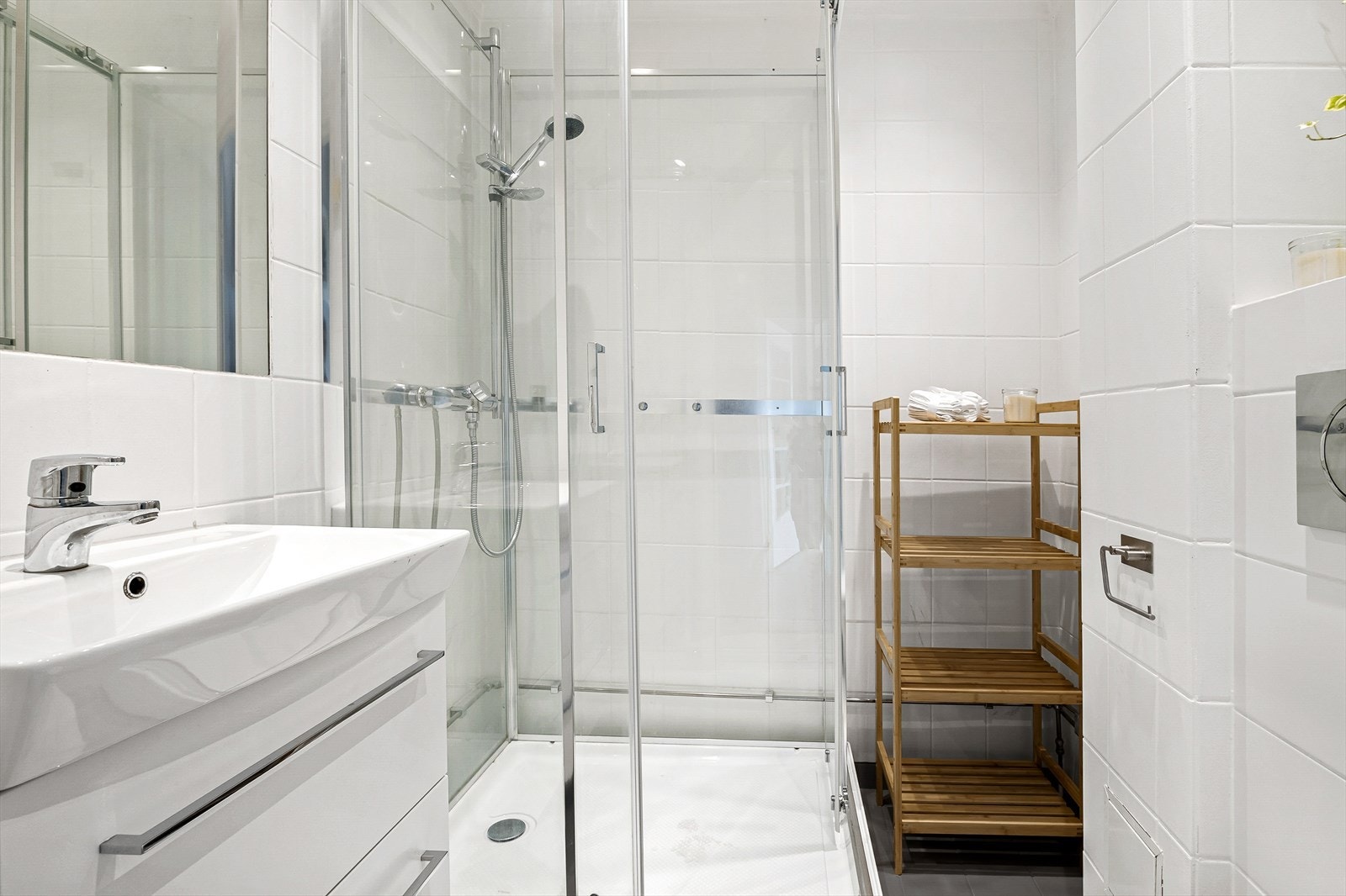 Pent bad med fliser på både gulv og vegger som skaper et rent og moderne inntrykk. Badet er innredet med et stilrent servantskap i hvit, glatt utførelse med en heldekkende servant og et speil som gir rommet en lys og romslig følelse. Galleribilde