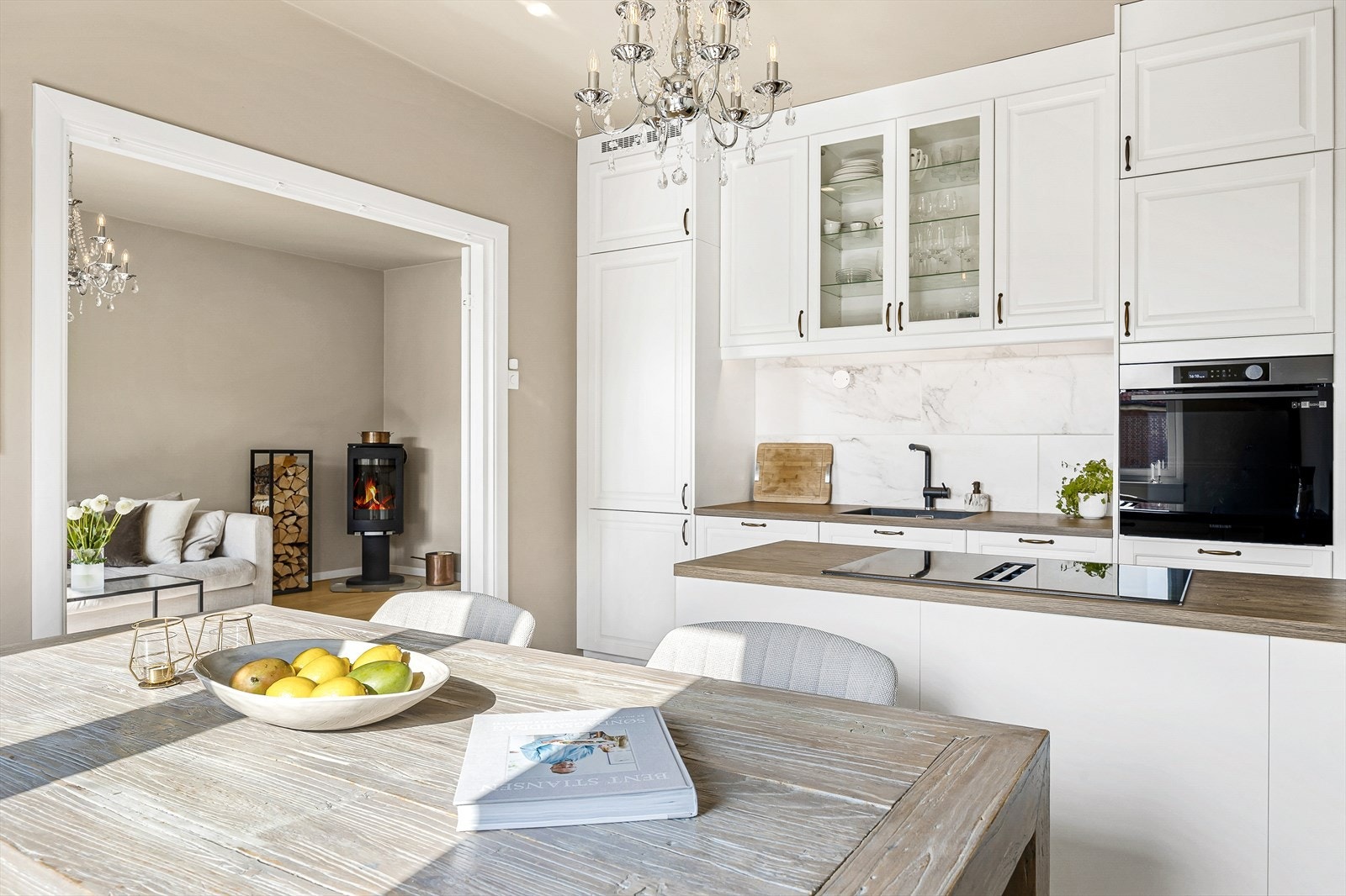 Moderne kjøkken fra 2023 med stilrene, hvite profilerte fronter som gir et tidløst og elegant uttrykk. Benkeplaten i laminat har en elegant, planlimt oppvaskkum med et praktisk 1-greps blandebatteri. Galleribilde