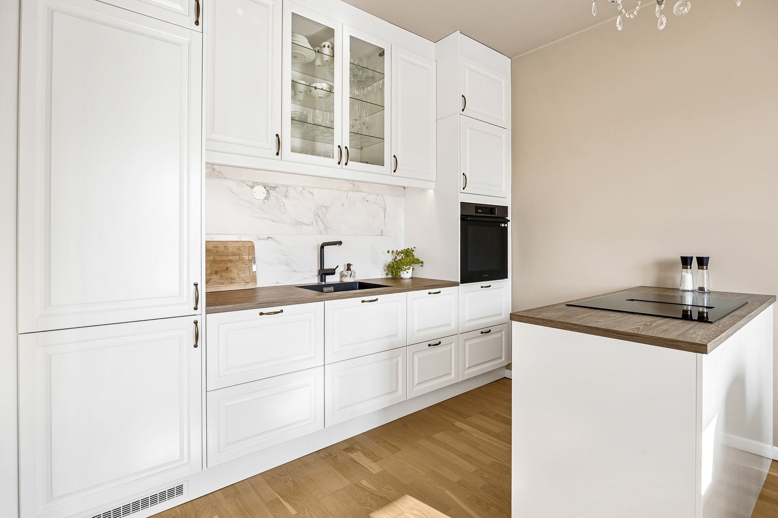 Veggen over benken er dekorert med stilige fliser som gir et eksklusivt preg. Kjøkkenet er utstyrt med integrerte hvitevarer som kjøl/frys, oppvaskmaskin, vinskap og stekeovn. Galleribilde