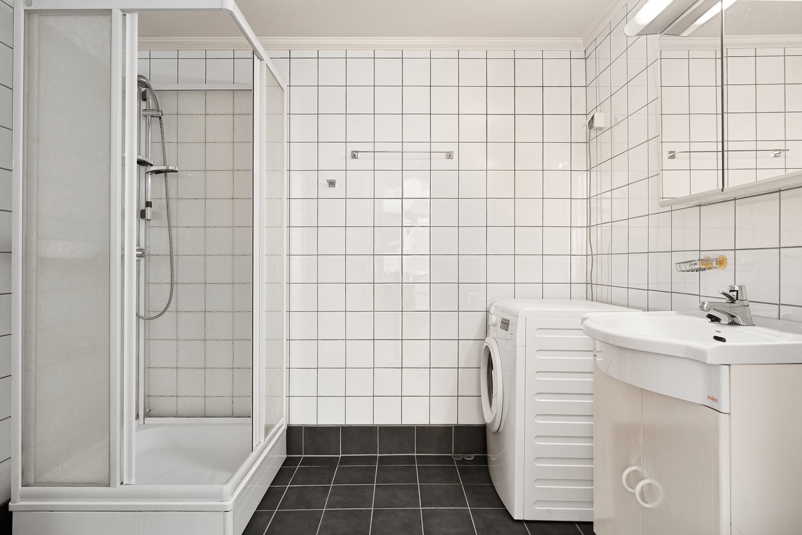 Badet er flislagt med gulvvarme og er utstyrt med dusjkabinett, vaskemaskin, servant og wc. Galleribilde