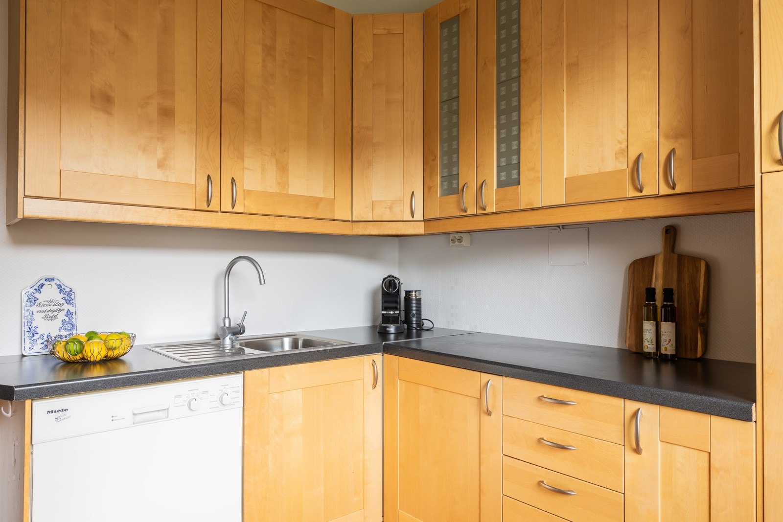 Kjøkkeninnredning med ett-speils finerte skapfronter og laminert benkeplate. Galleribilde