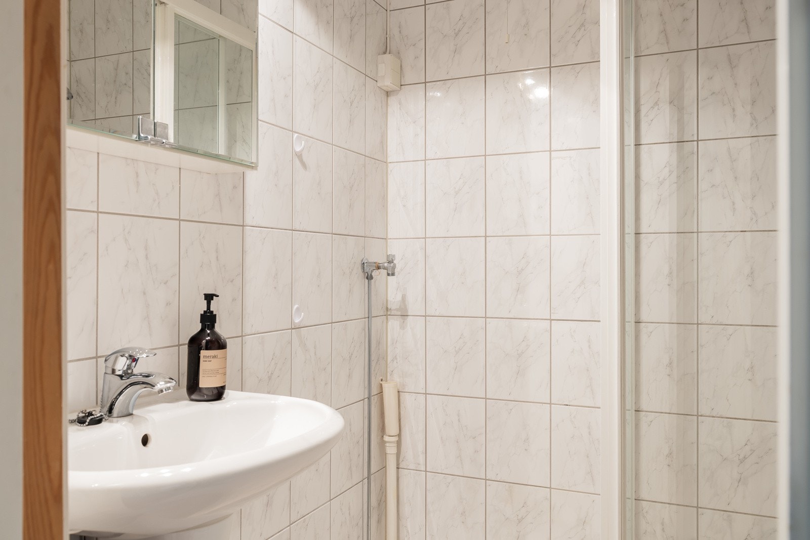 Baderomsinnredningen er bestående av søyleservant, speilskap med overlys, dusjhjørne med skyvedører, vegghengt klosett og opplegg for vaskemaskin. Galleribilde