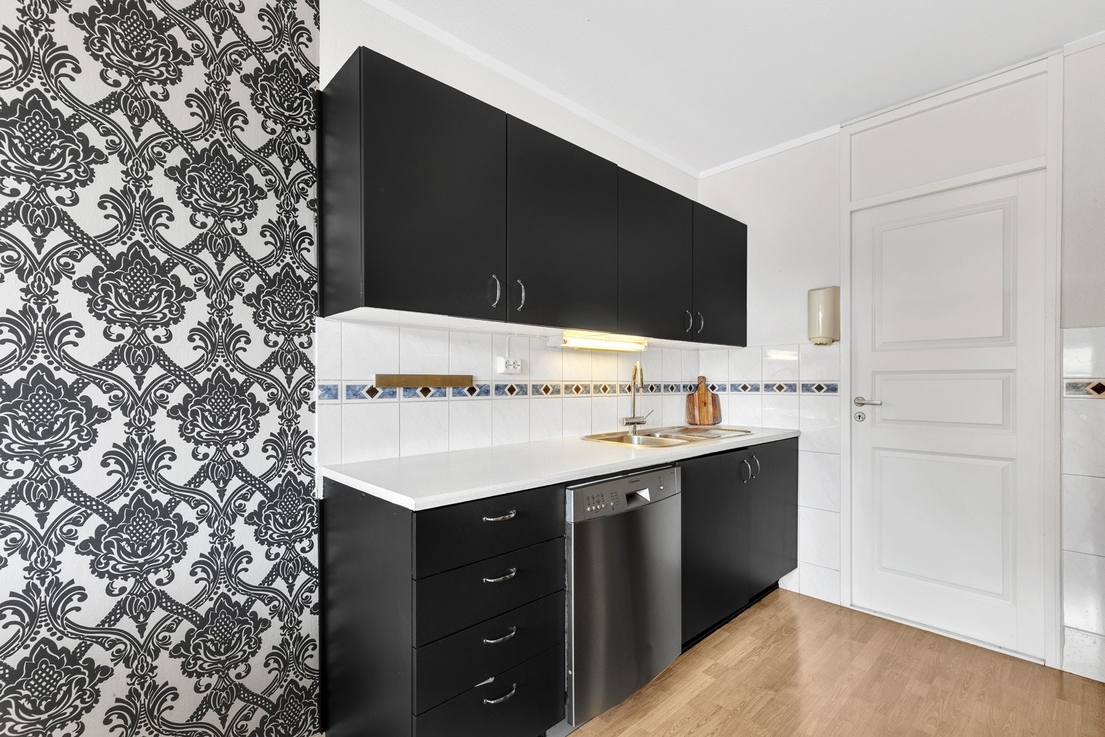 Kjøkkenet er svart med glatte fronter og hvit benkeplate. Galleribilde