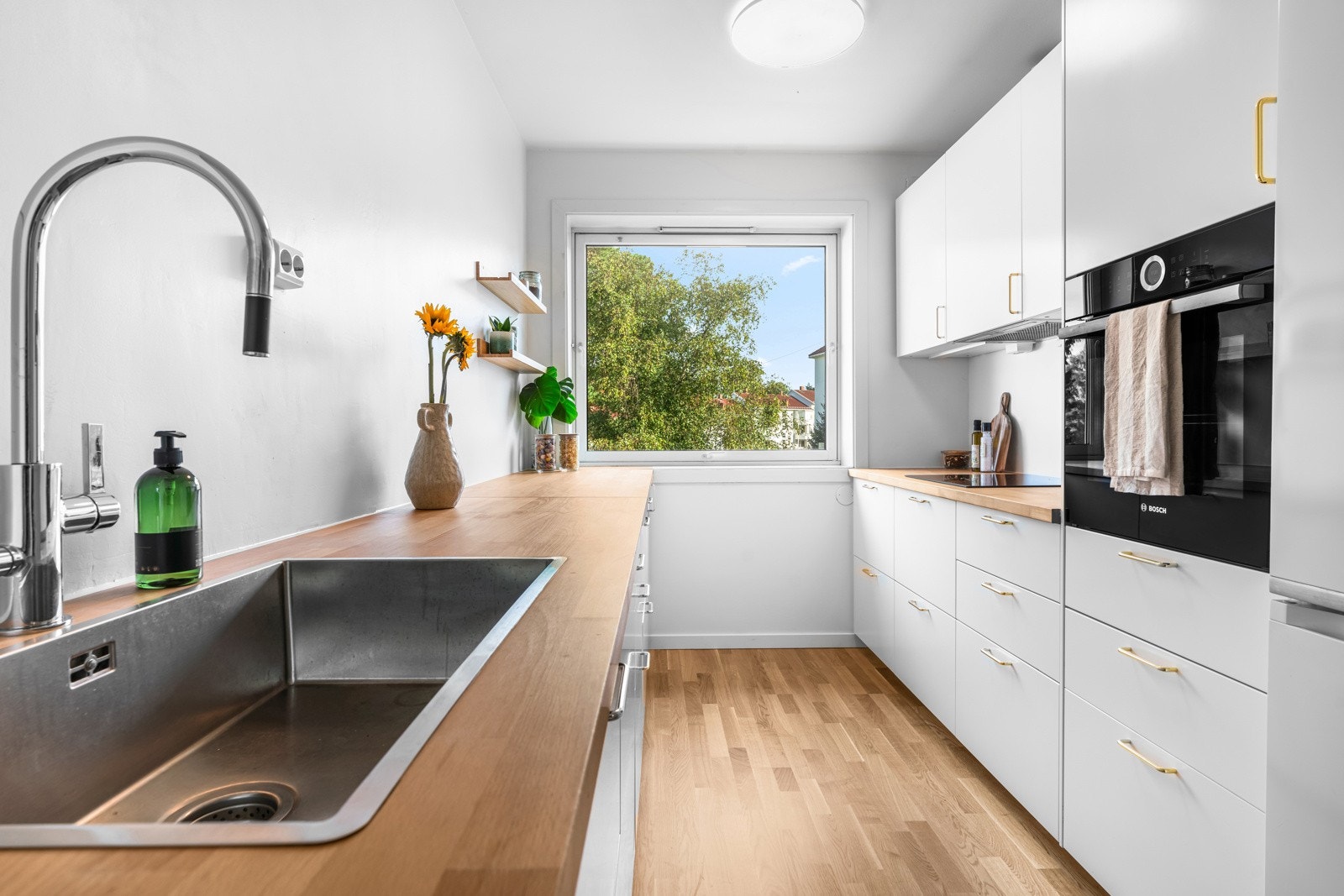 Praktisk separat kjøkken med stilren kjøkkeninnredning med slette fronter og benkeplate i heltre. Galleribilde