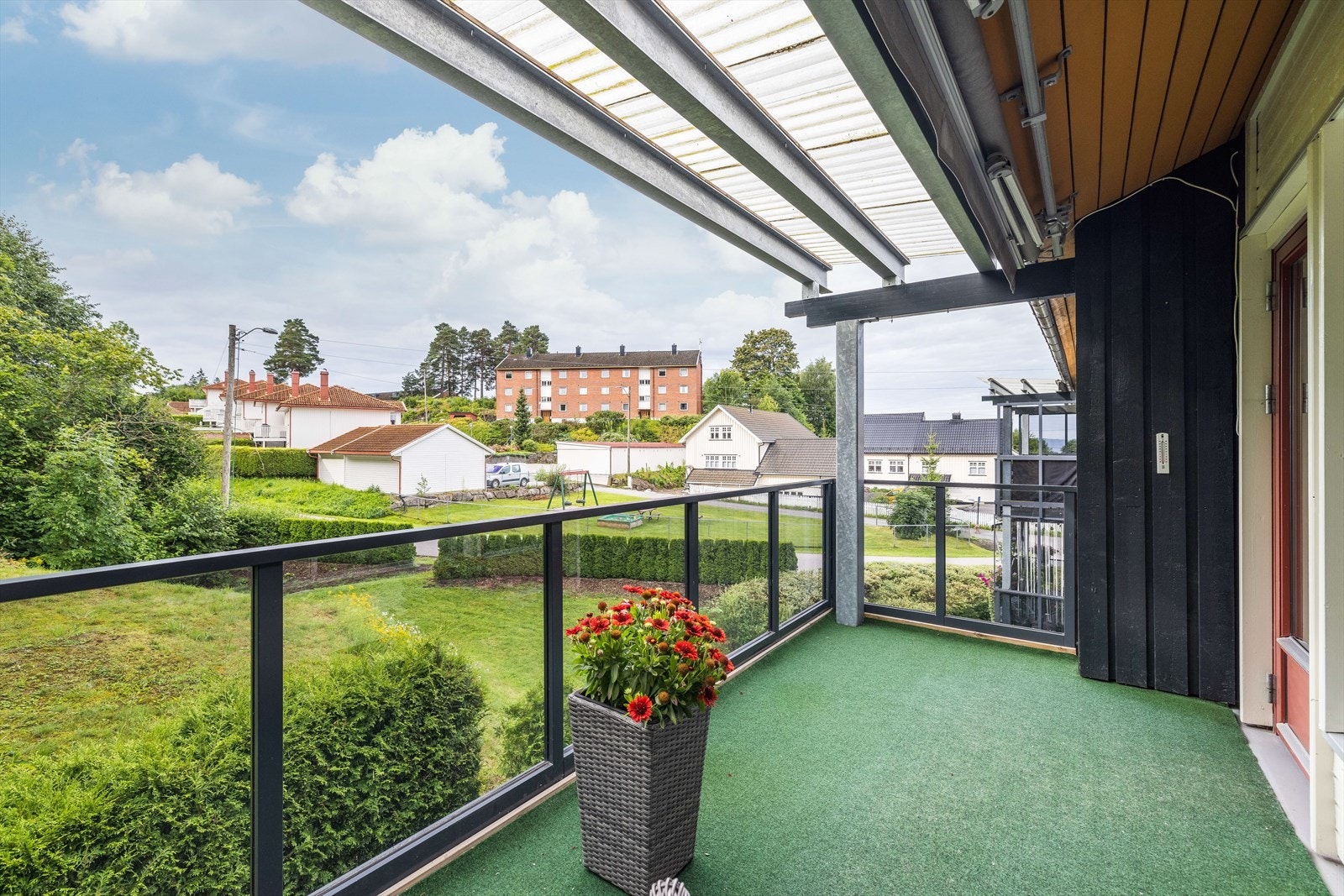 Verandaen har takoverbygg som øker bruksmuligheten og det er glassrekkverk rundt som gir fint utsyn til grøntarealer på utsiden. I tillegg er det montert en elektrisk markise som gir ytterligere skjerming ved behov. Galleribilde