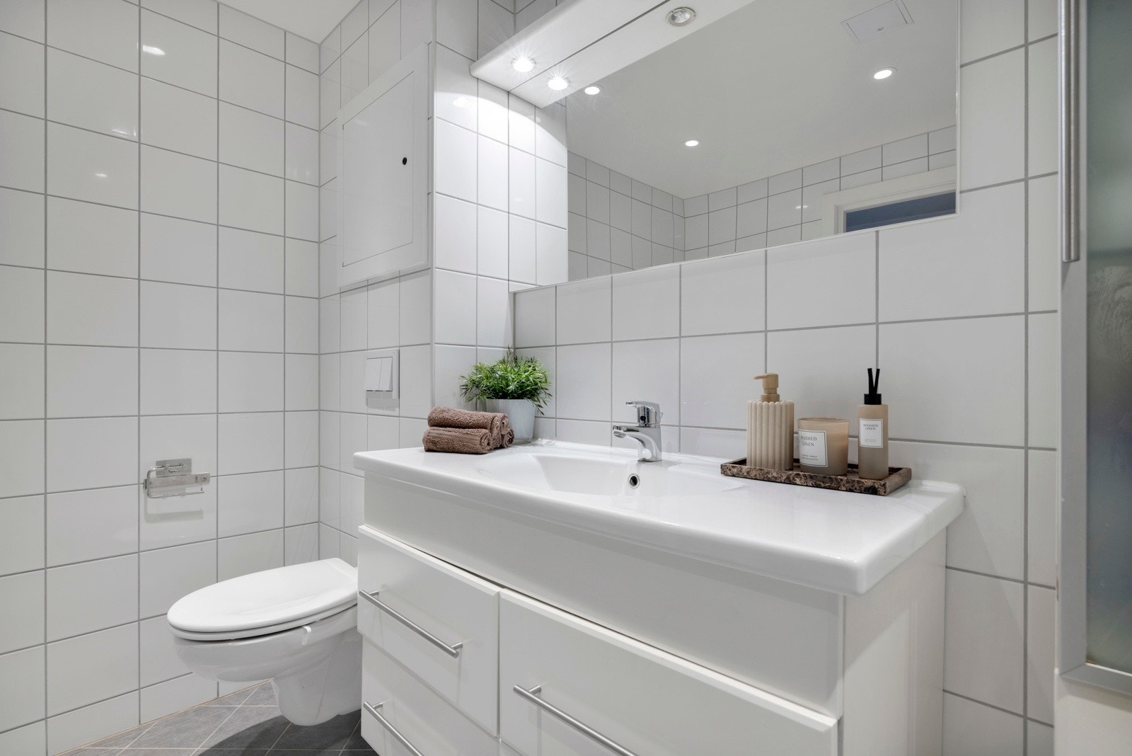 Badet er innredet med vegghengt toalett, deilig regnfallsdusj og et romslig, baderomsmøblement med god plass til de viktige tingene og speil med belysning over Galleribilde