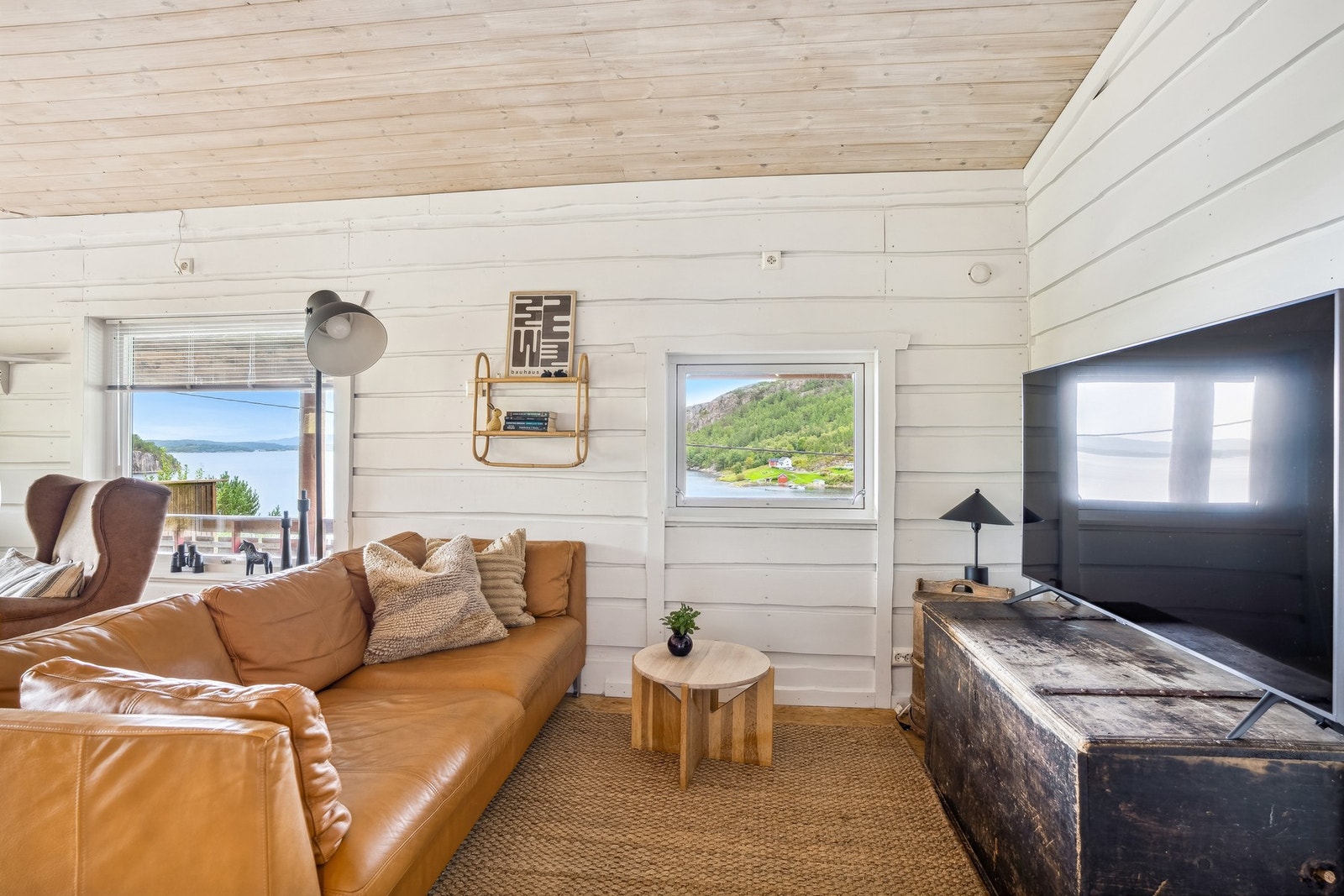 Hvitmalte panelvegger gir et delikat uttrykk og bidrar til den åpne atmosfæren i stuen. Galleribilde