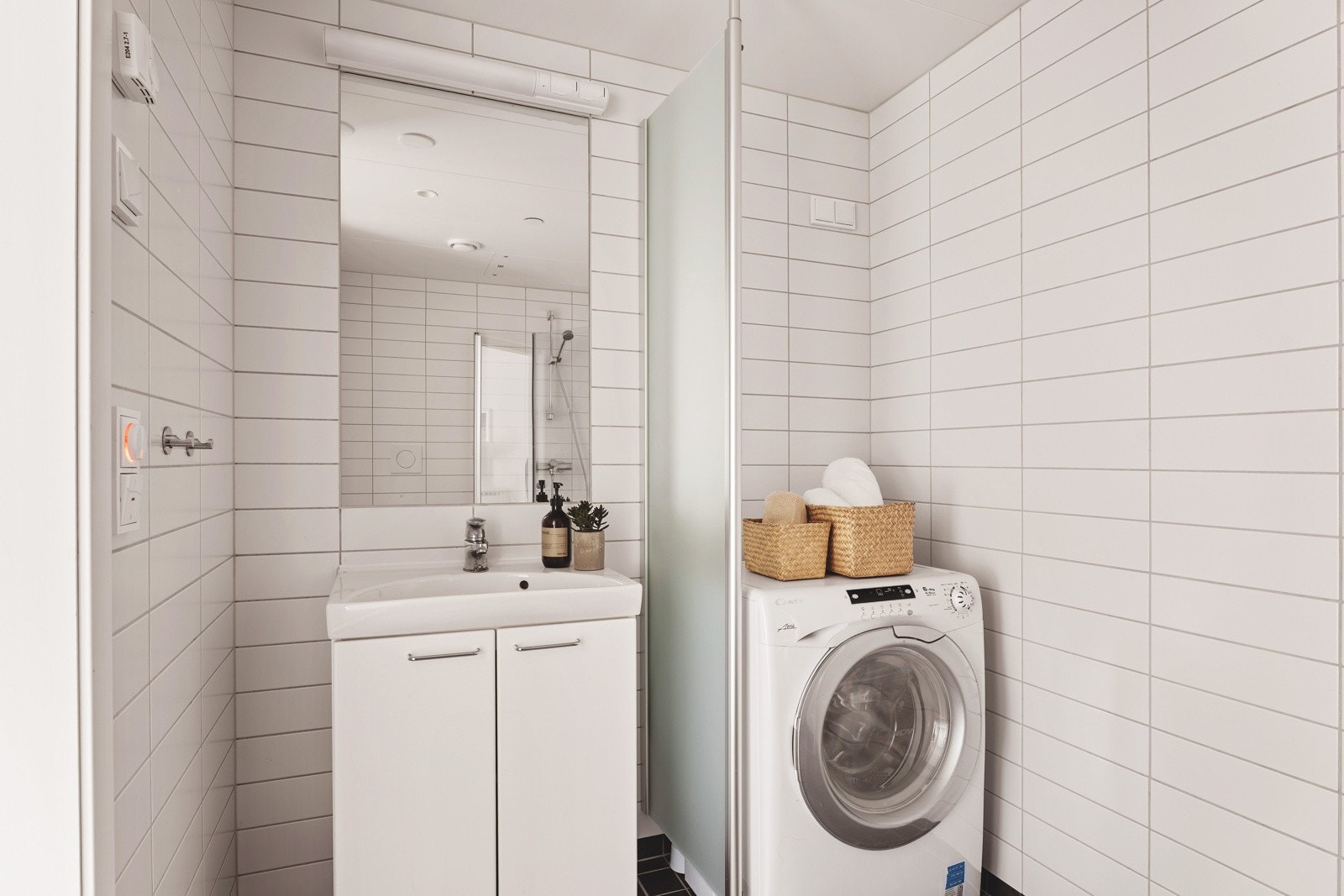 Flislagt bad med veggmontert toalett og dusjdører i herdet glass. Galleribilde