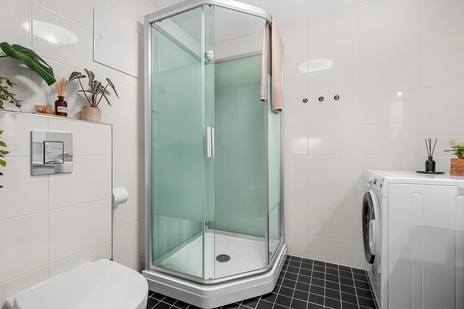 Badet er utstyrt med servantskap, mekanisk avtrekk, opplegg for vaskemaskin, veggmontert wc og dusjkabinett Galleribilde